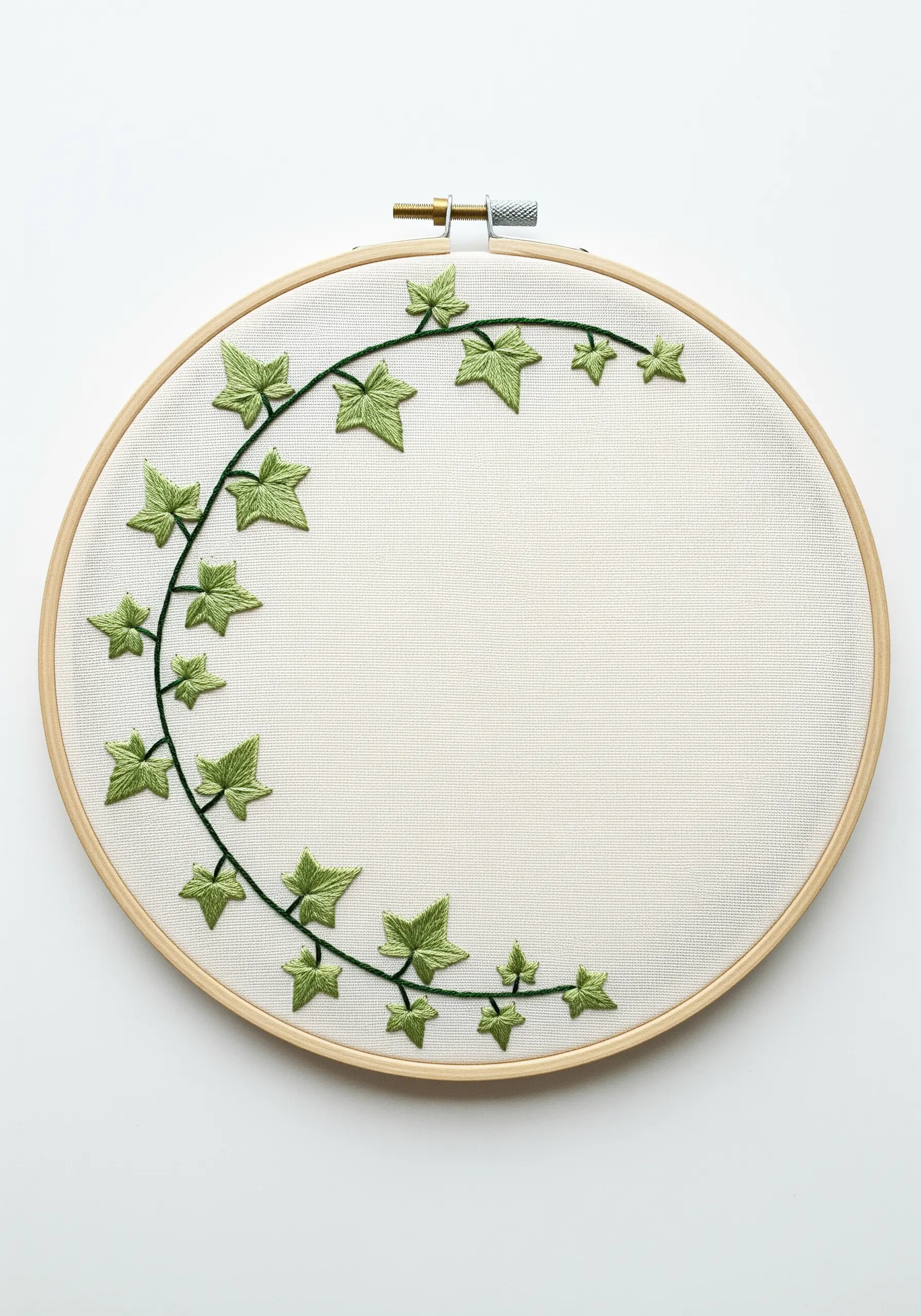 A simple, asymmetrical ivy vine embroidered in shades of green on off-white fabric.