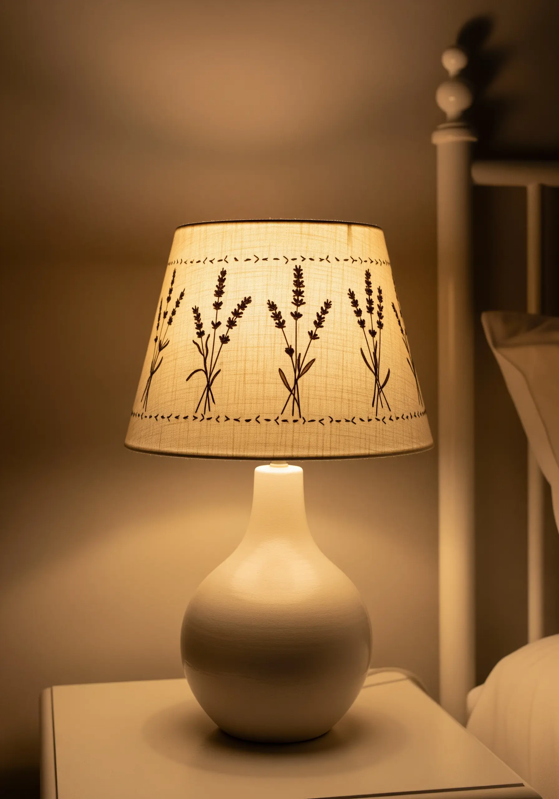 A linen lampshade with a simple, repeating pattern of embroidered lavender stalks.