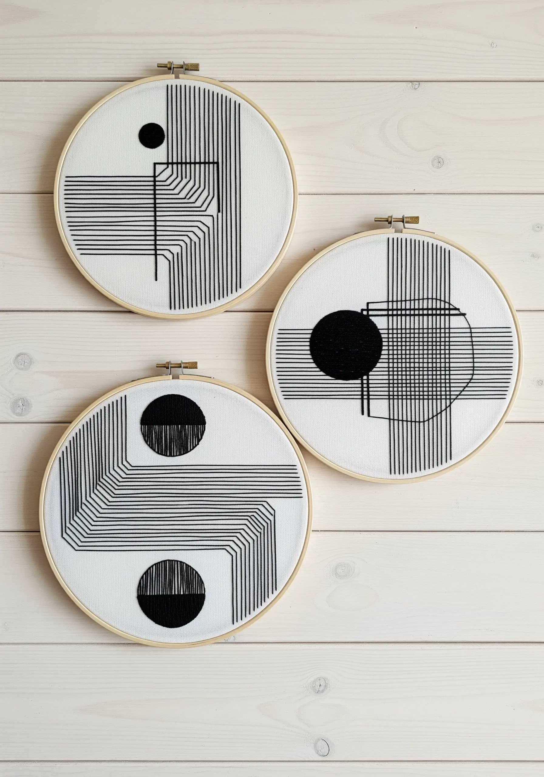 A trio of hoops with black and white Op Art designs featuring lines and circles.