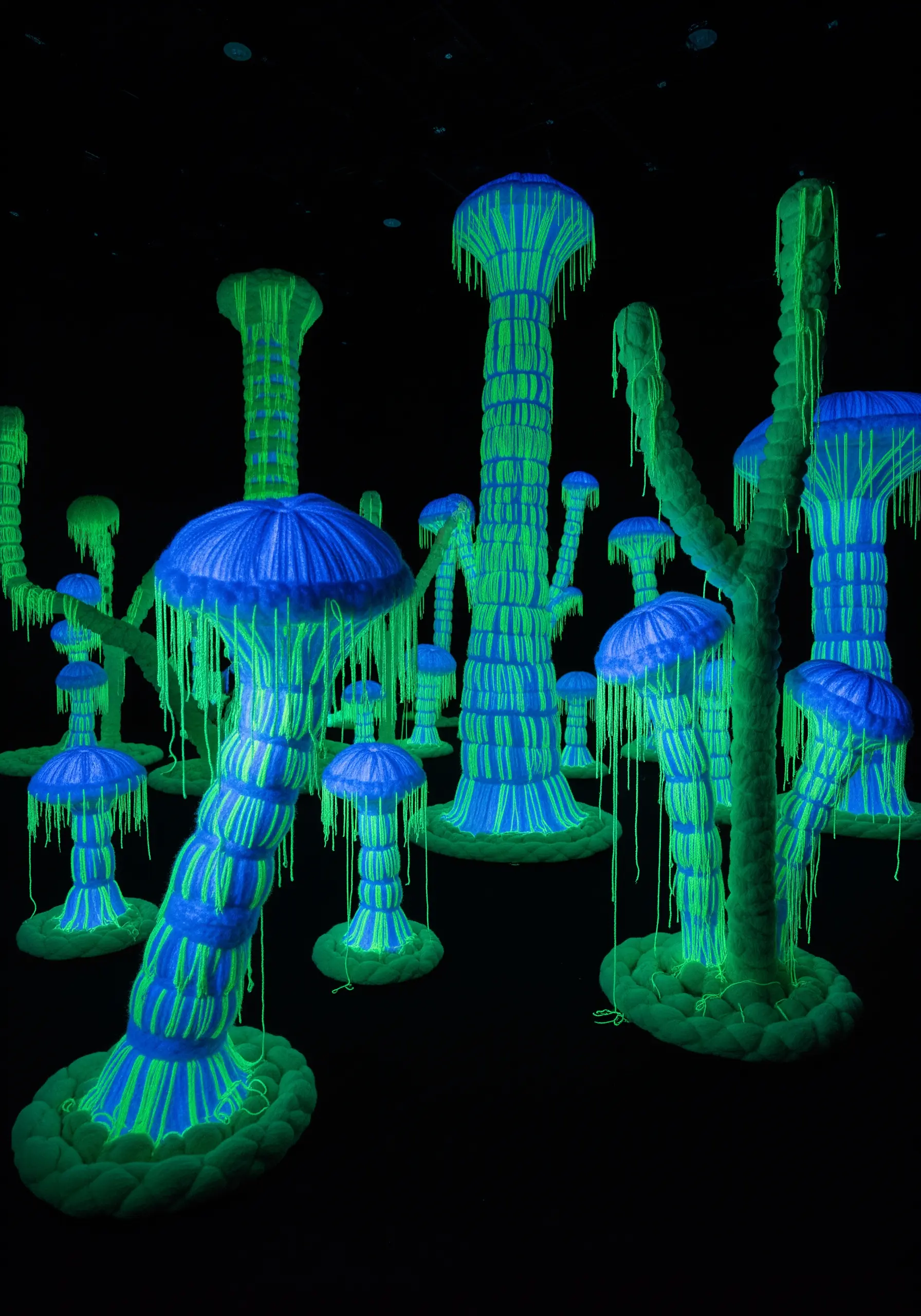 An embroidered mushroom stitched with UV-reactive thread glowing under a blacklight.
