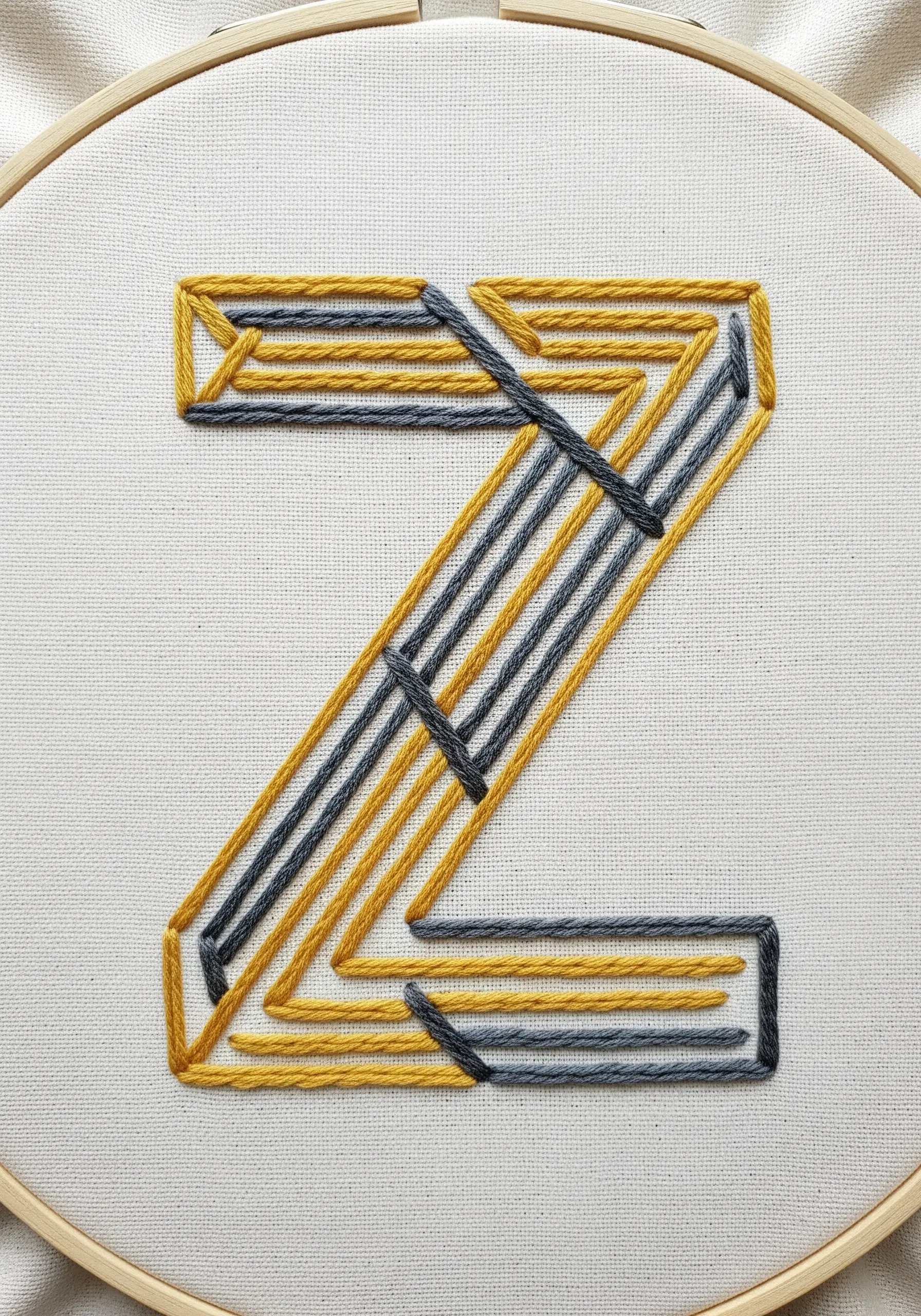 A geometric letter 'Z' created with intersecting yellow and grey straight stitches.