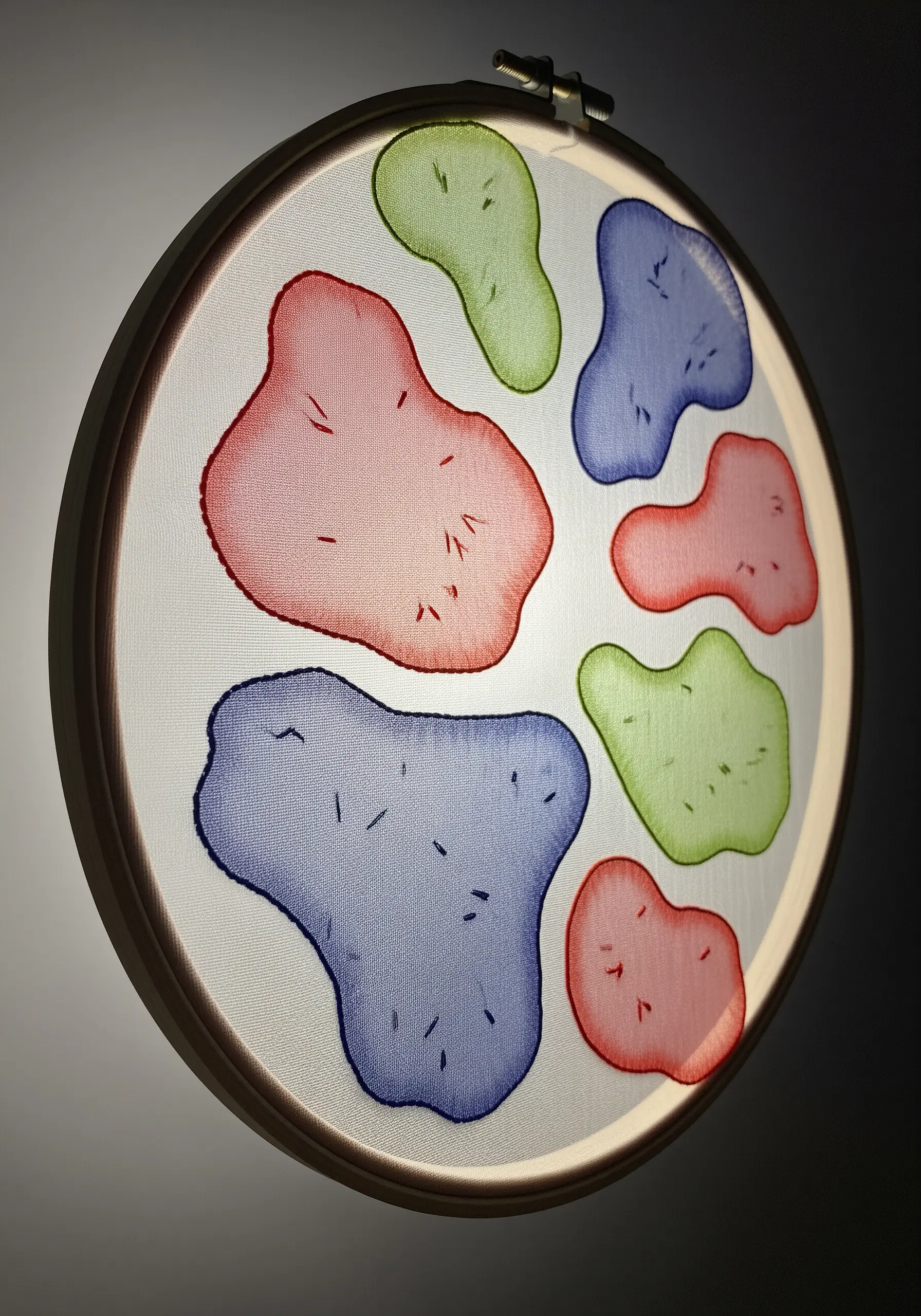 Backlit embroidery on sheer fabric with soft, glowing abstract color shapes.