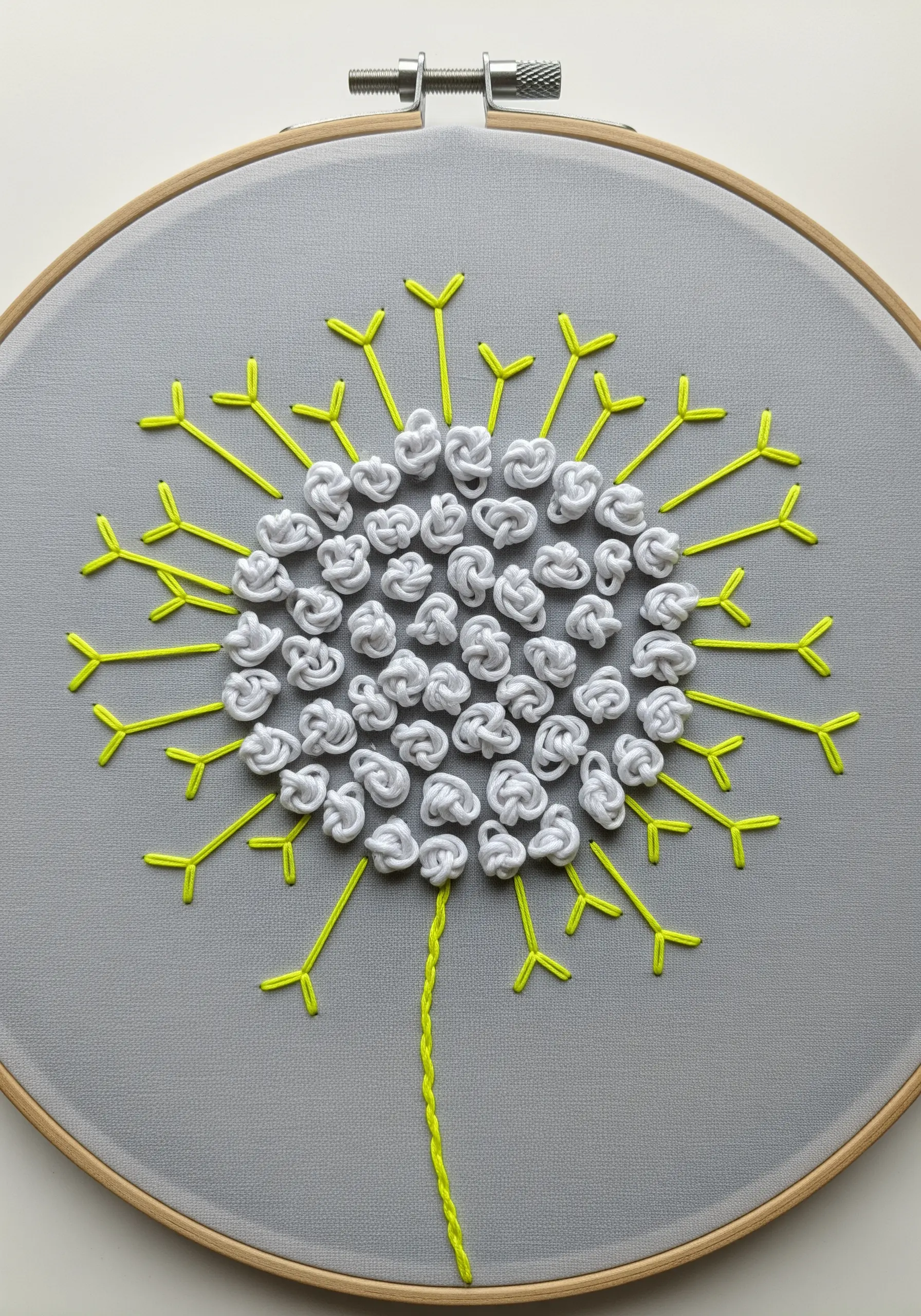 A stylized dandelion with 3D white knots for seeds and neon green stitched stems.