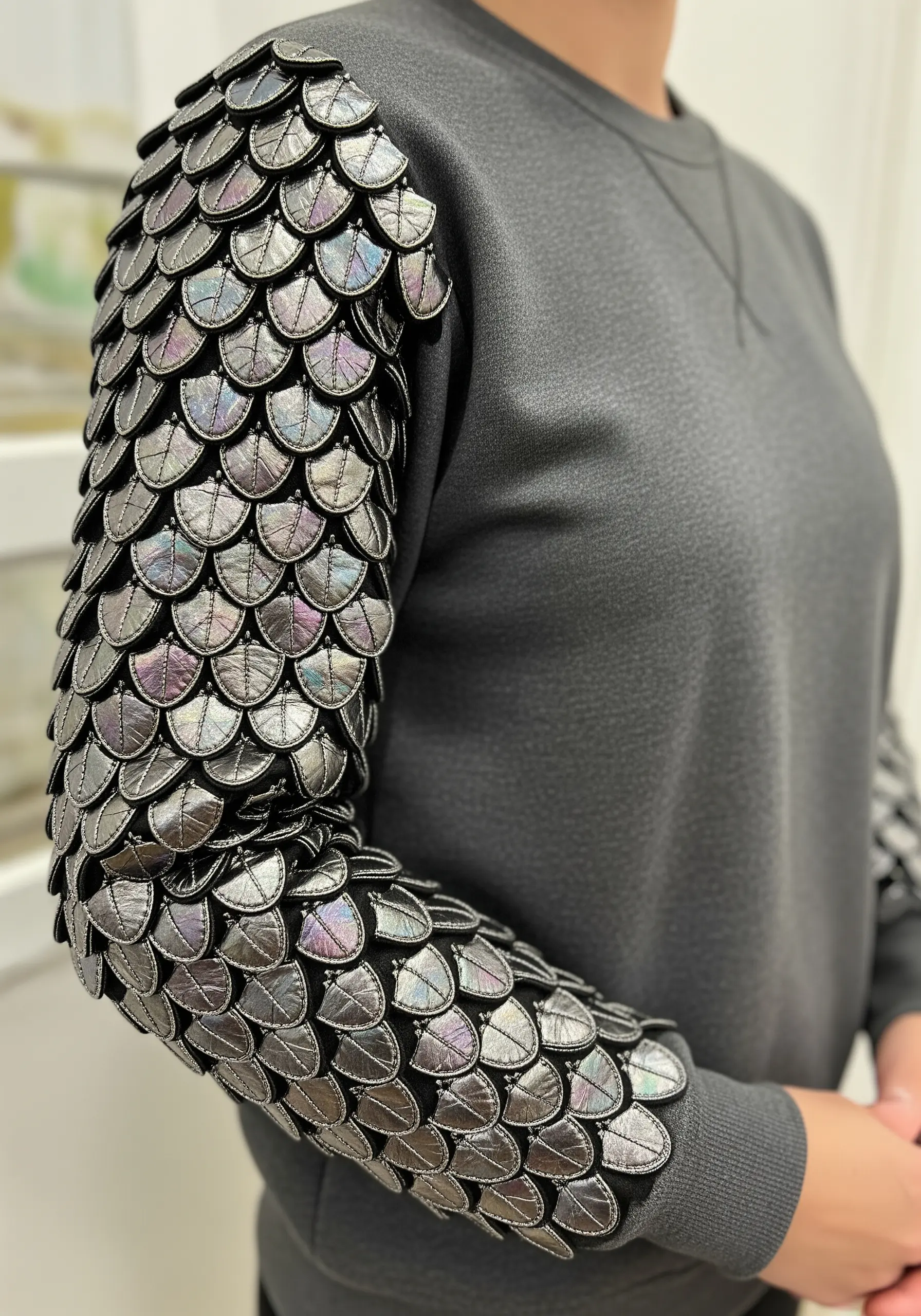 A full sleeve covered in overlapping, padded scales made from iridescent metallic fabric.