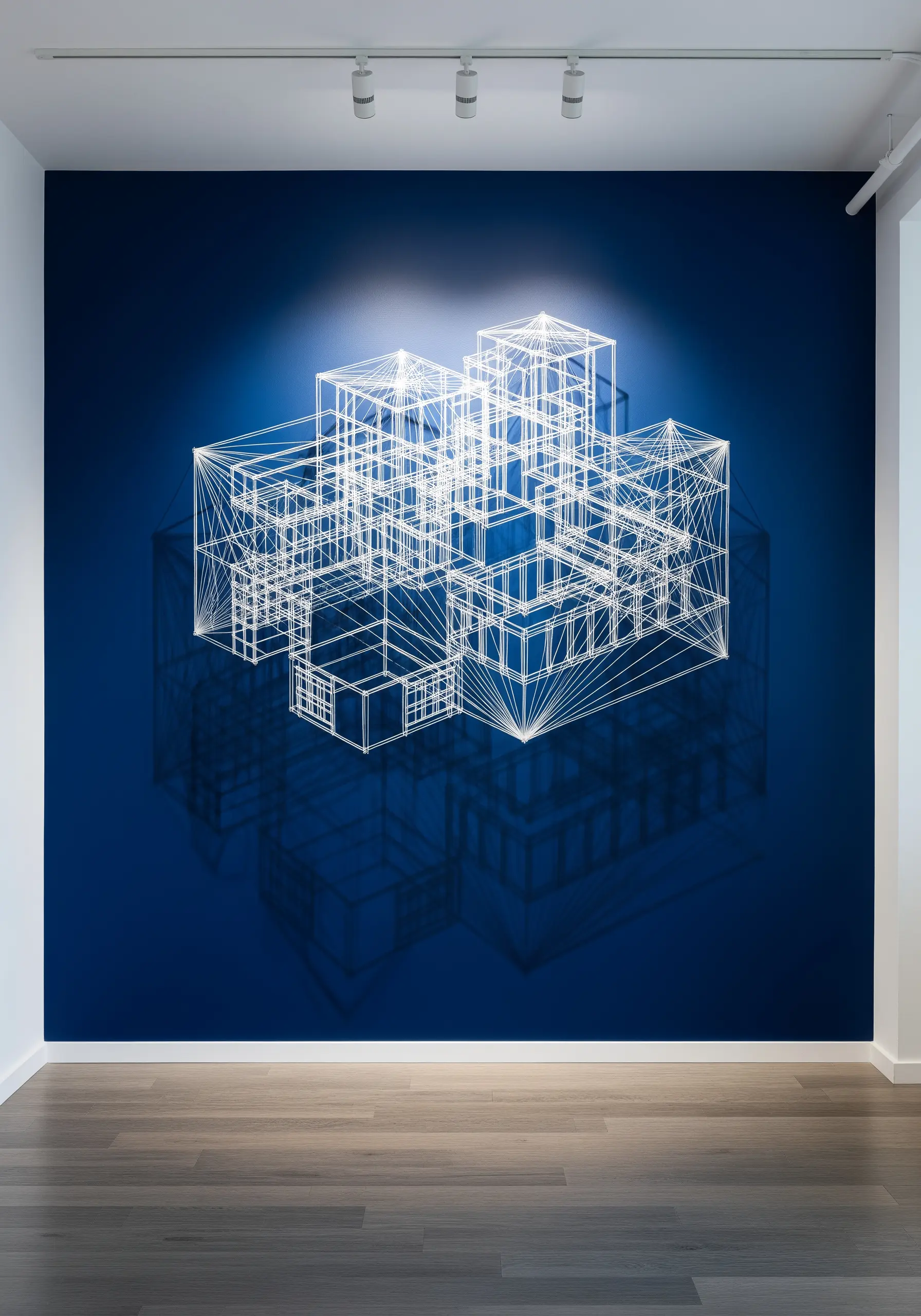 A glowing white thread installation of a geometric building against a dark blue wall.