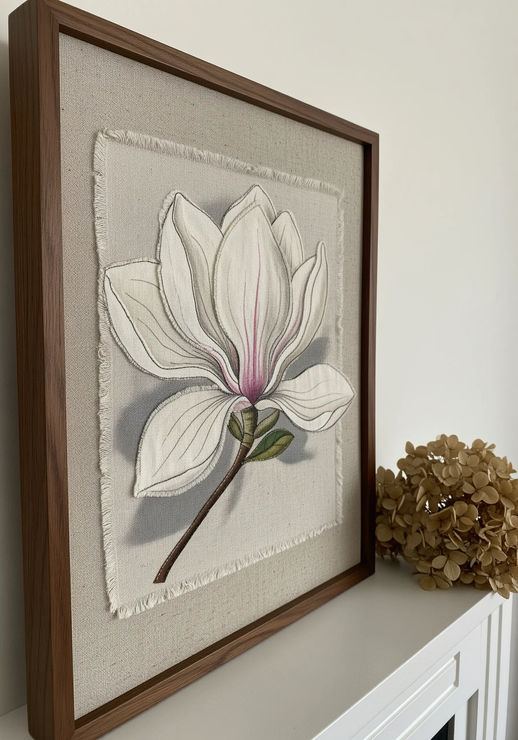 Framed magnolia appliqué with fine line embroidery details and a frayed linen edge.