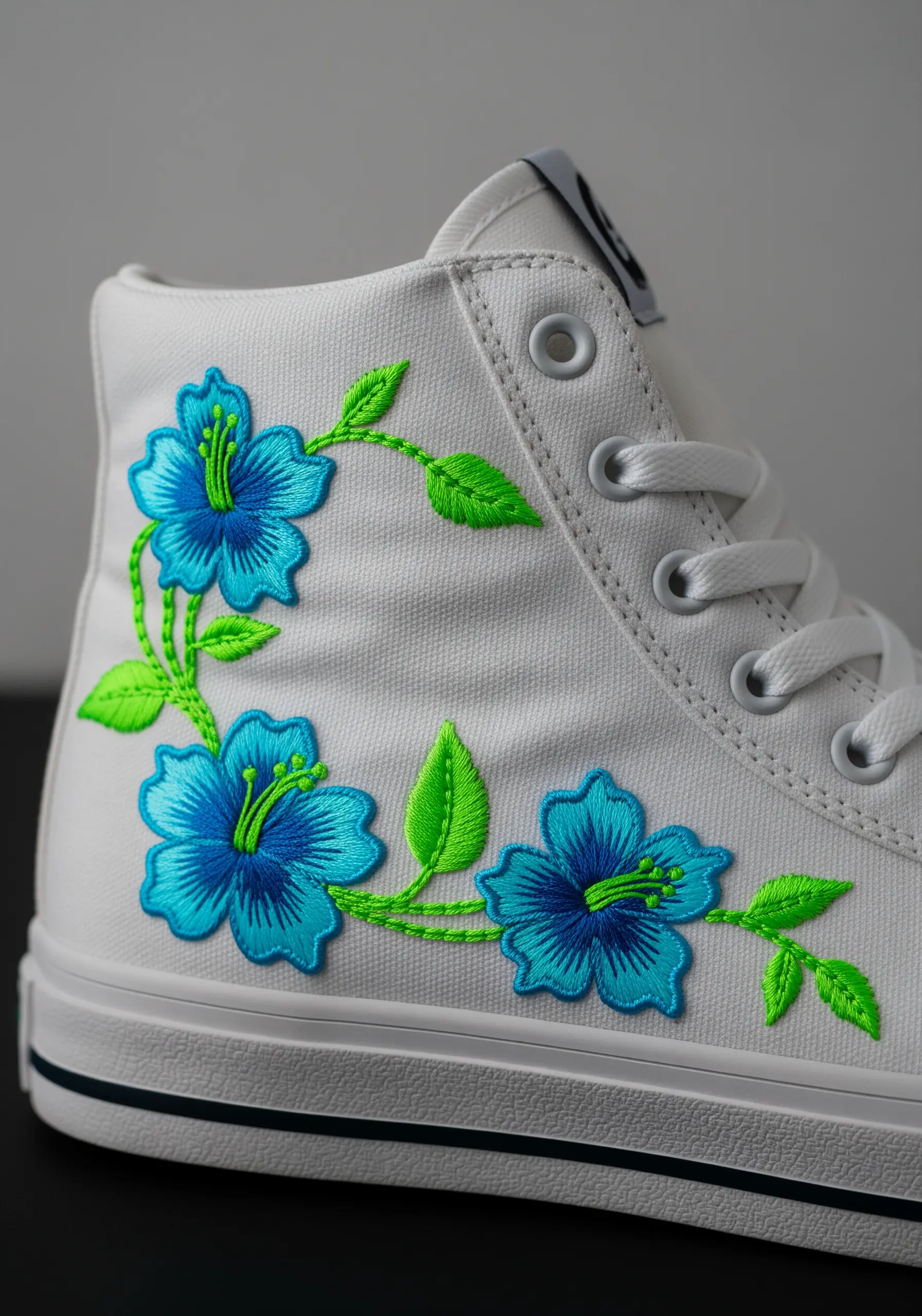 Bright blue and turquoise hibiscus flowers with neon green stems embroidered on a white sneaker.