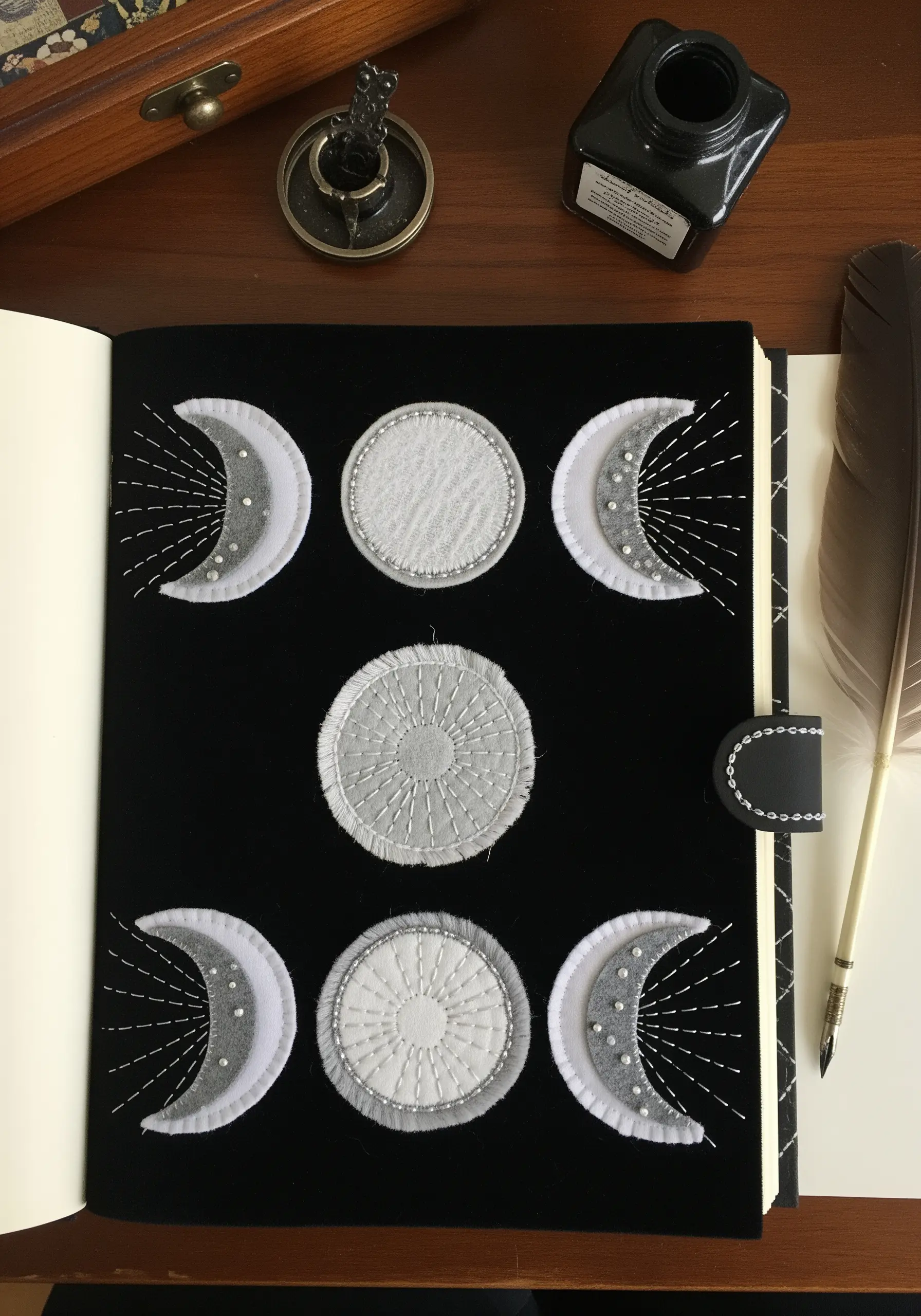 Appliquéd moon phases on a black journal cover with beadwork details.