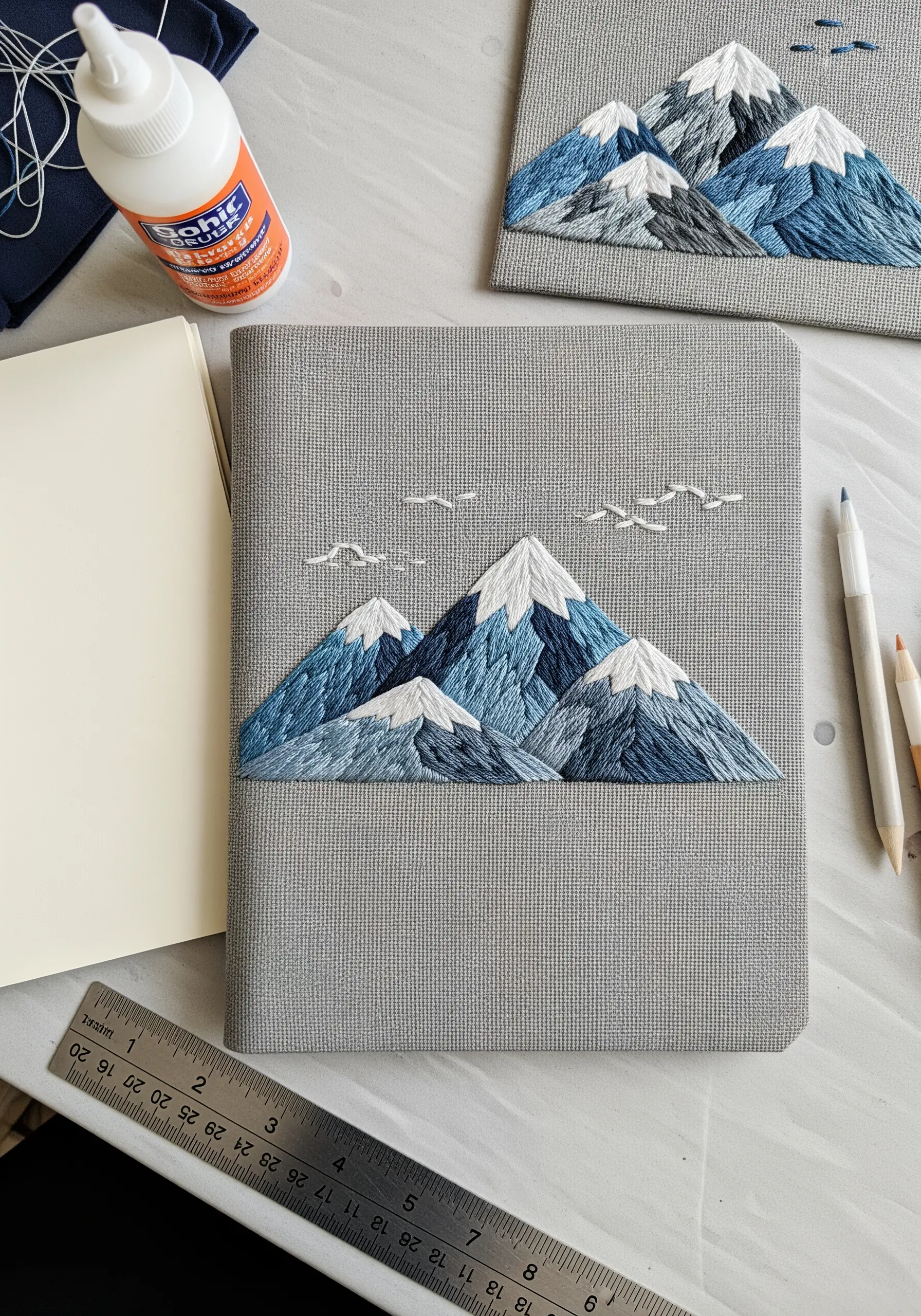 A fabric-covered journal with a beautifully embroidered mountain range scene