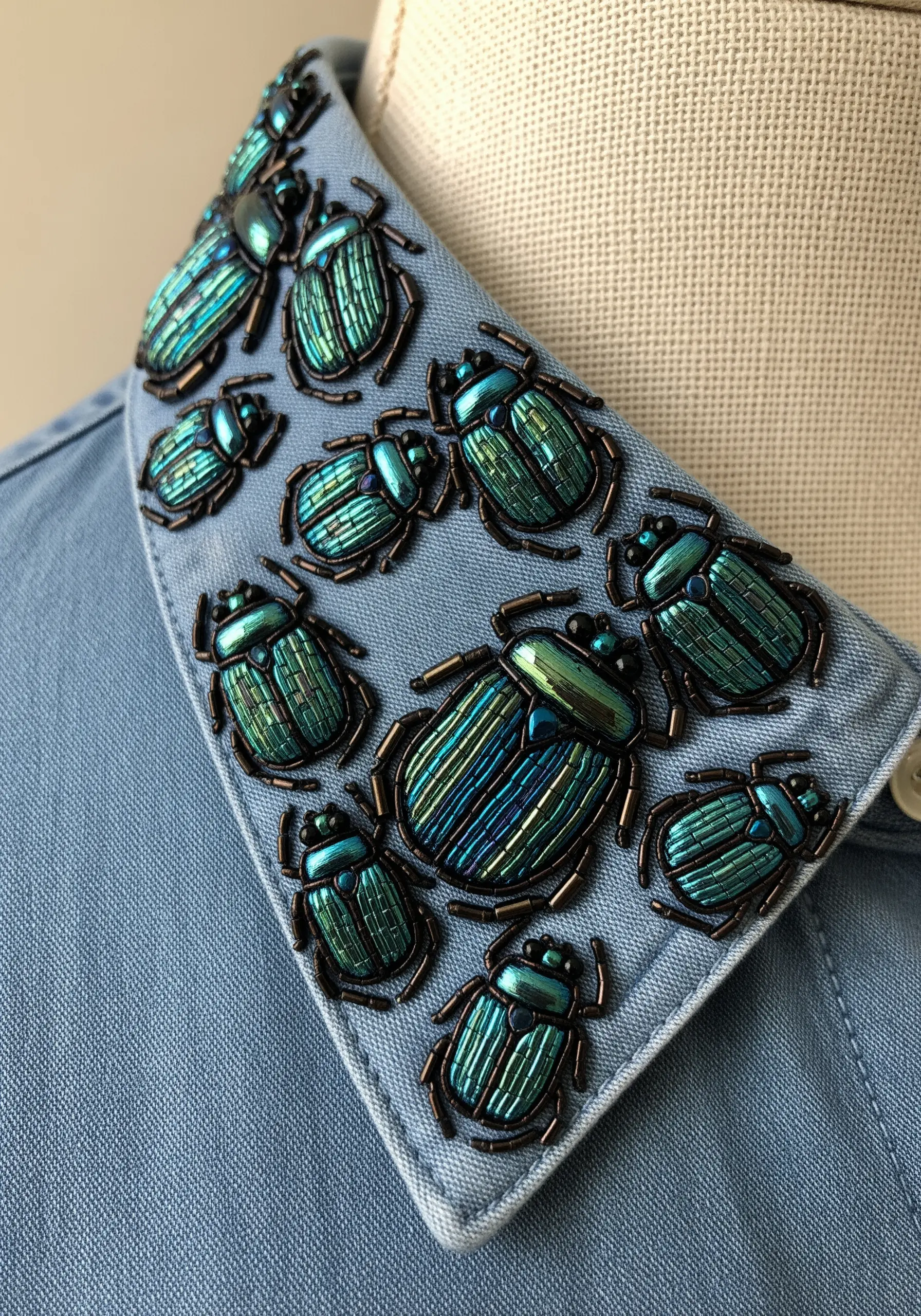 A blue shirt collar heavily embellished with intricately beaded iridescent beetles.