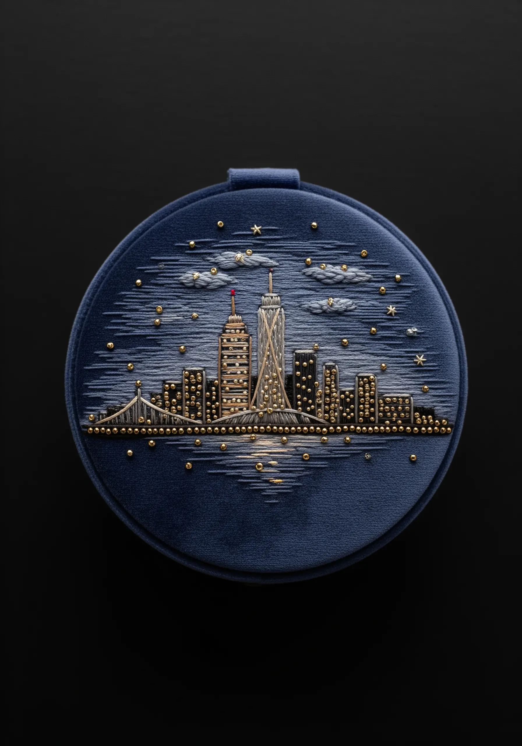 A detailed cityscape on a blue velvet jewelry box lid, embellished with gold beads.