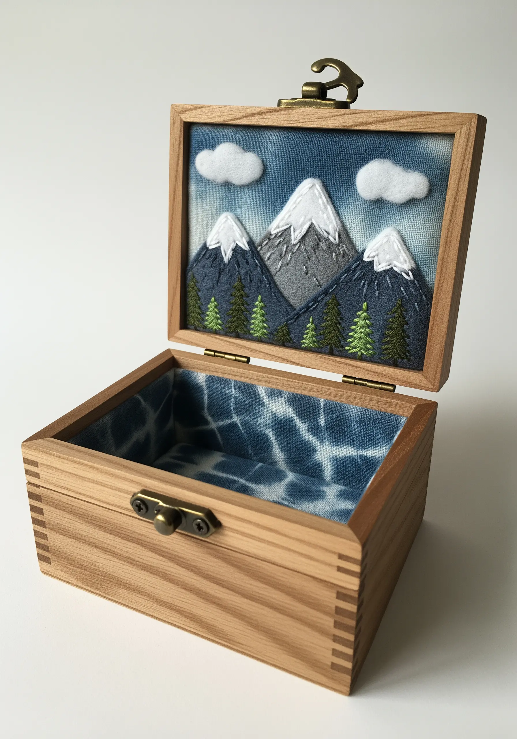 A small wooden box with an embroidered mountain scene set inside the lid.