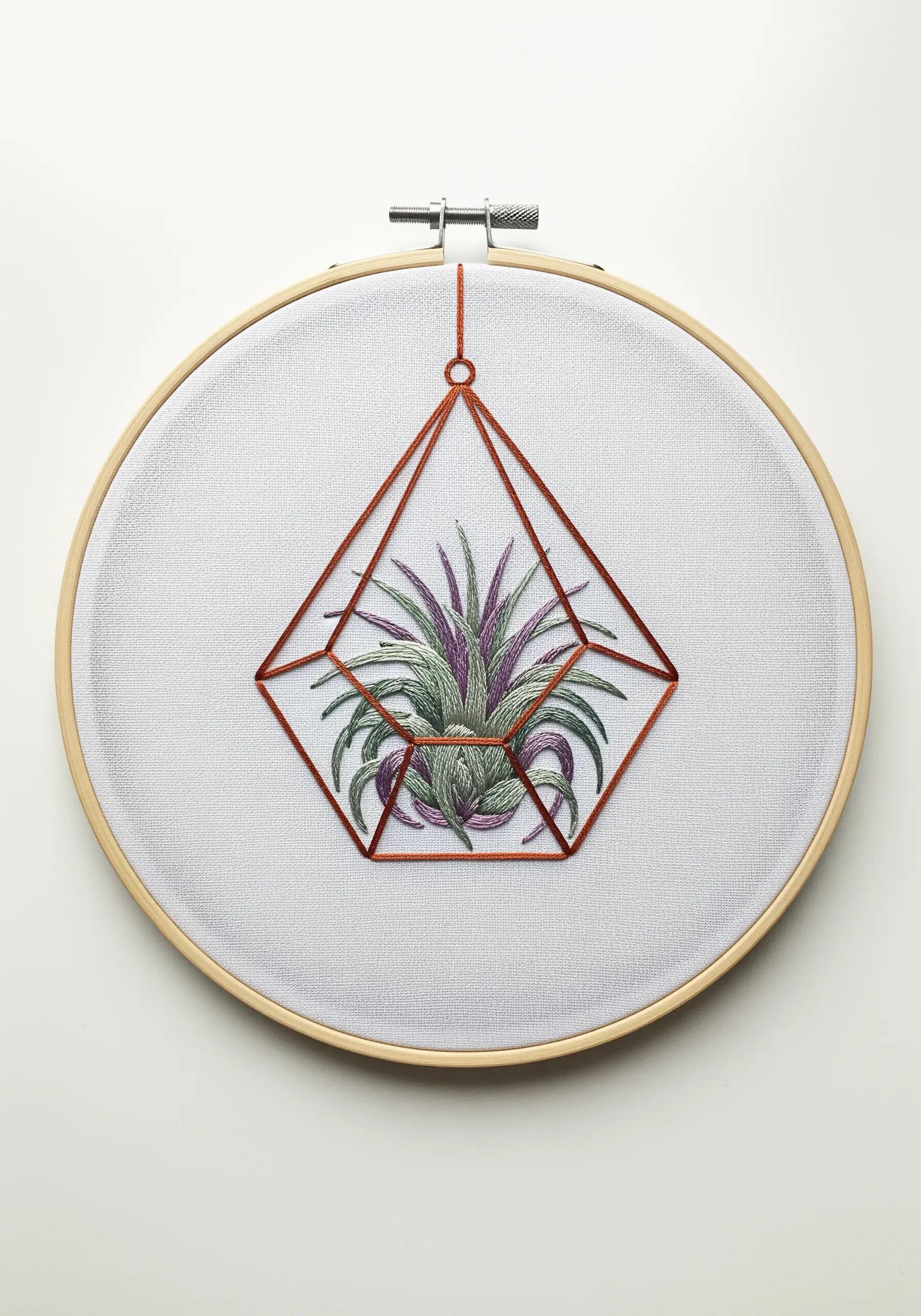 Minimalist embroidery of a single air plant in a geometric copper terrarium