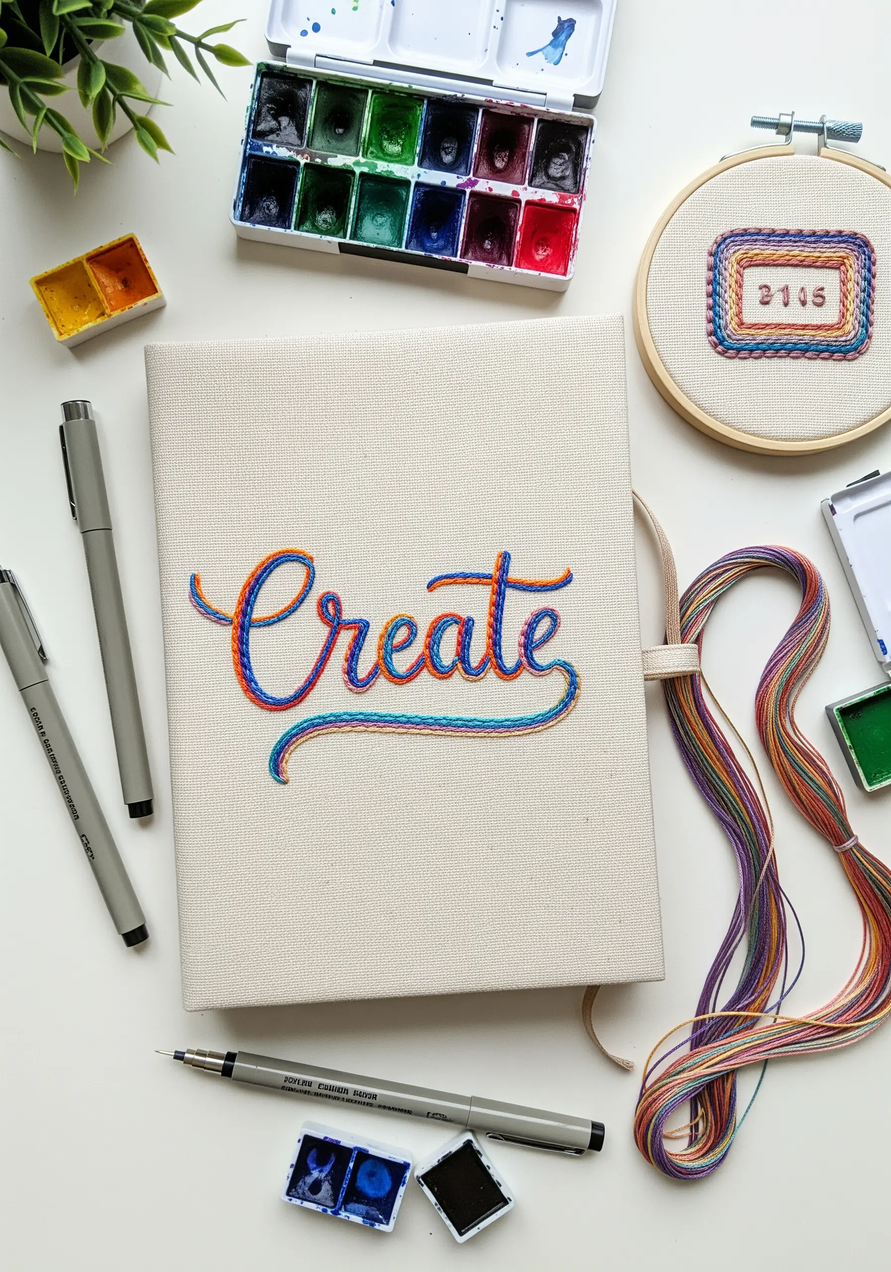 The word 'Create' embroidered on a journal cover using colorful variegated thread in a chain stitch.