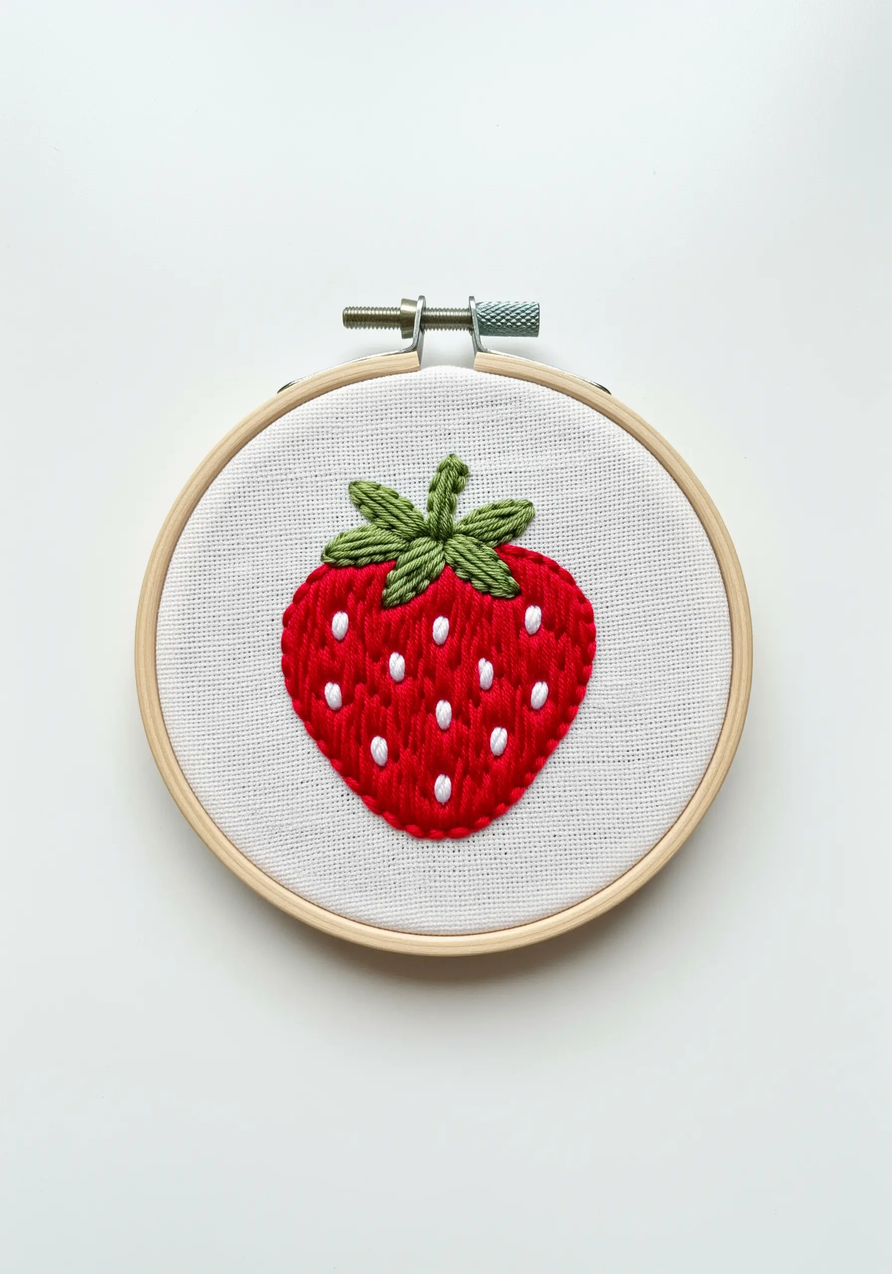 A bright red strawberry with a smooth satin stitch fill and white seed details.