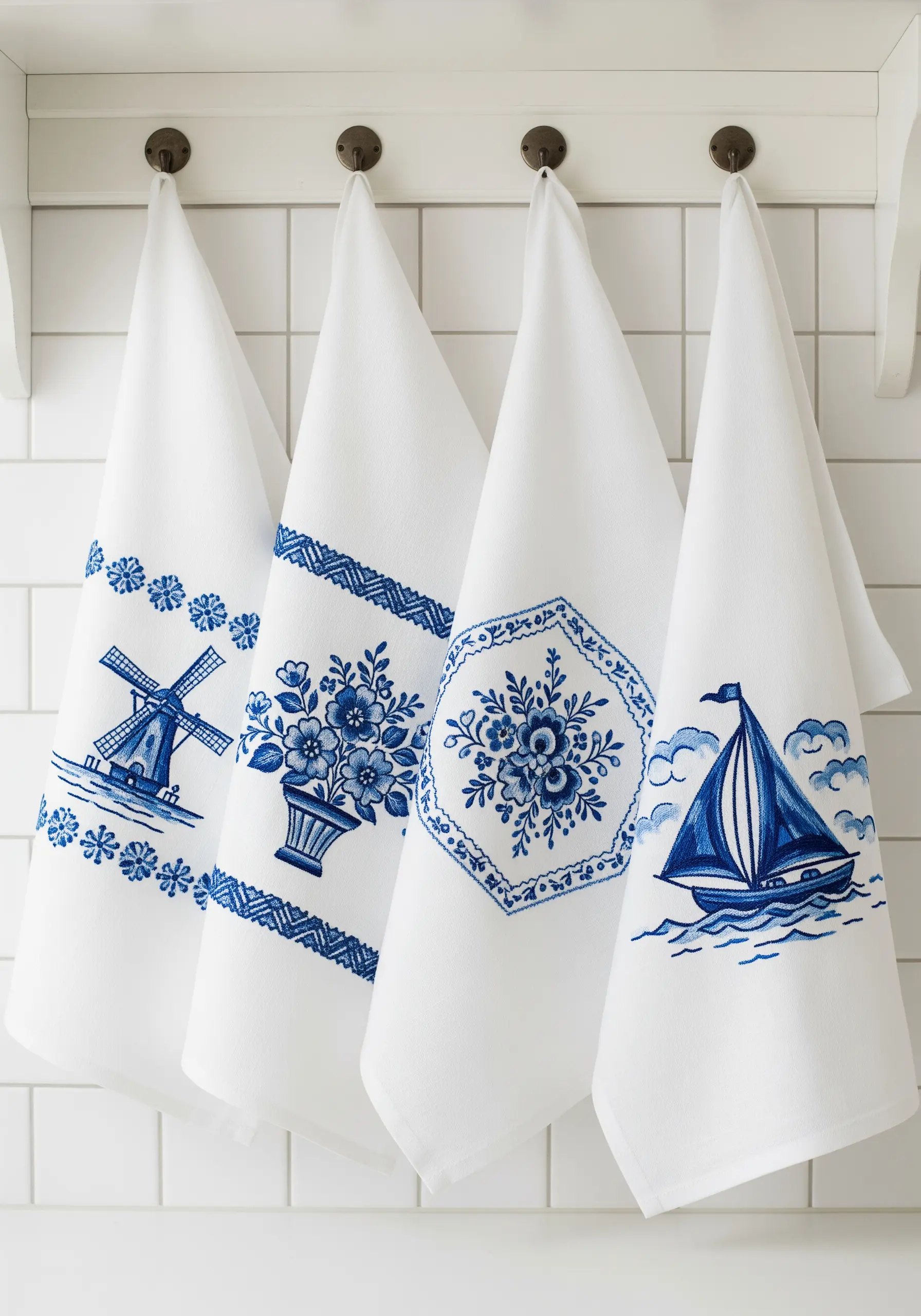 Four white kitchen towels with different embroidery designs in classic Delft Blue.