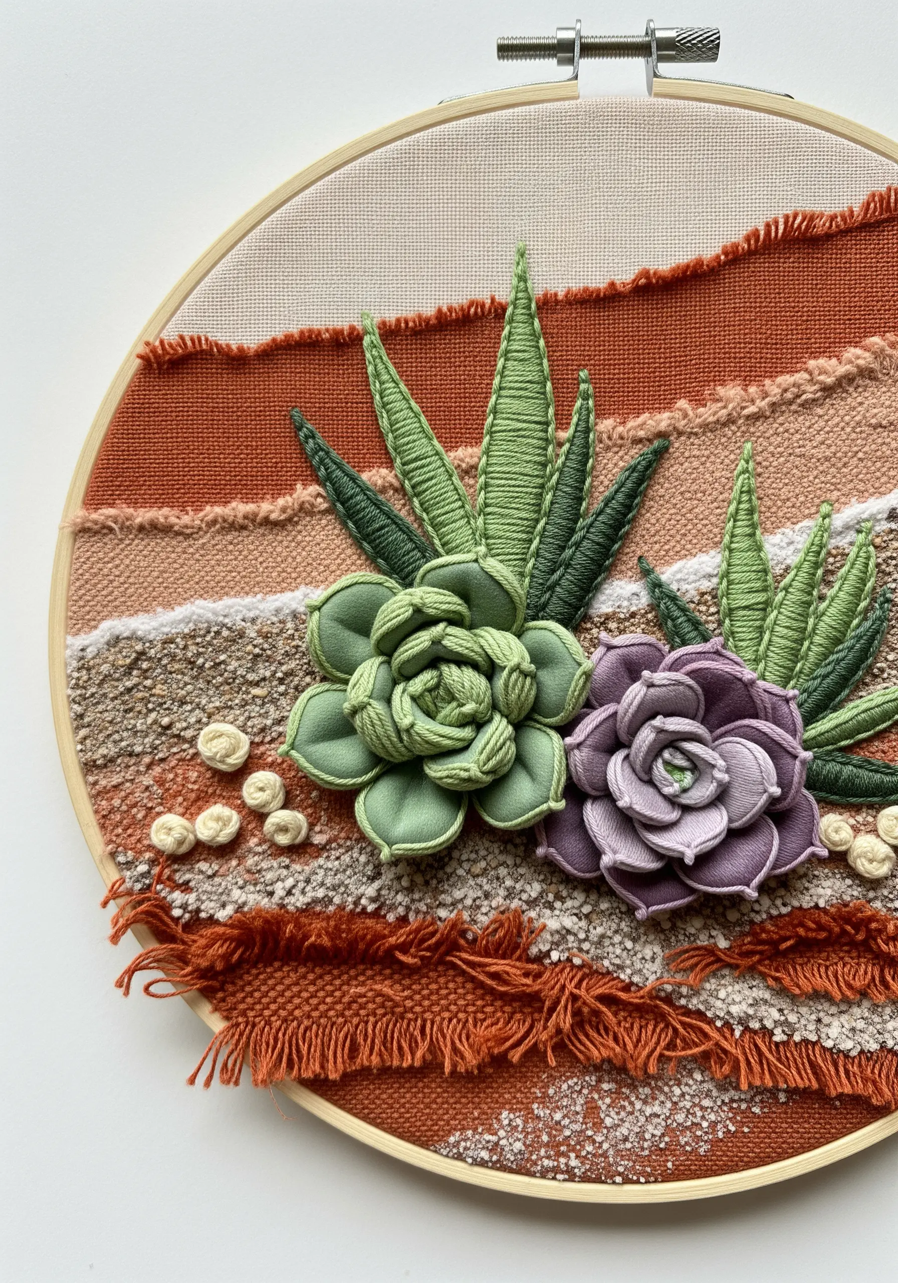 Dimensional embroidered succulents on a woven background of earth-toned fabric strips.