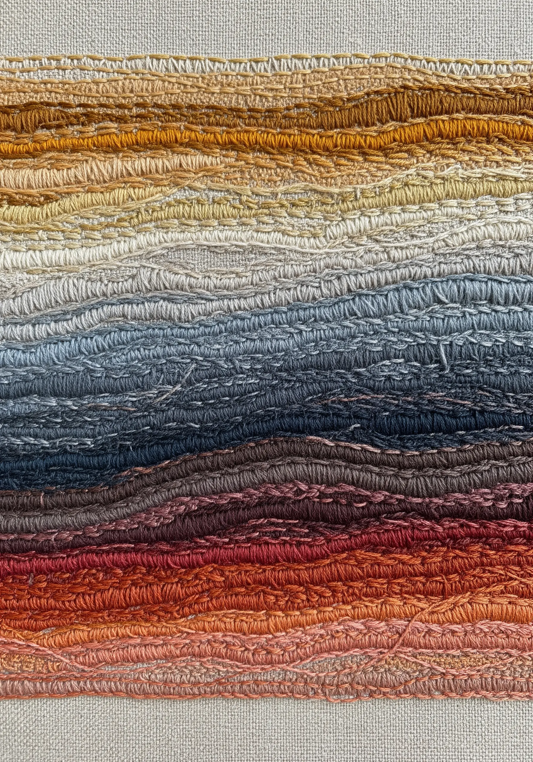 A highly textured abstract landscape embroidery with horizontal bands of earthy color gradients.