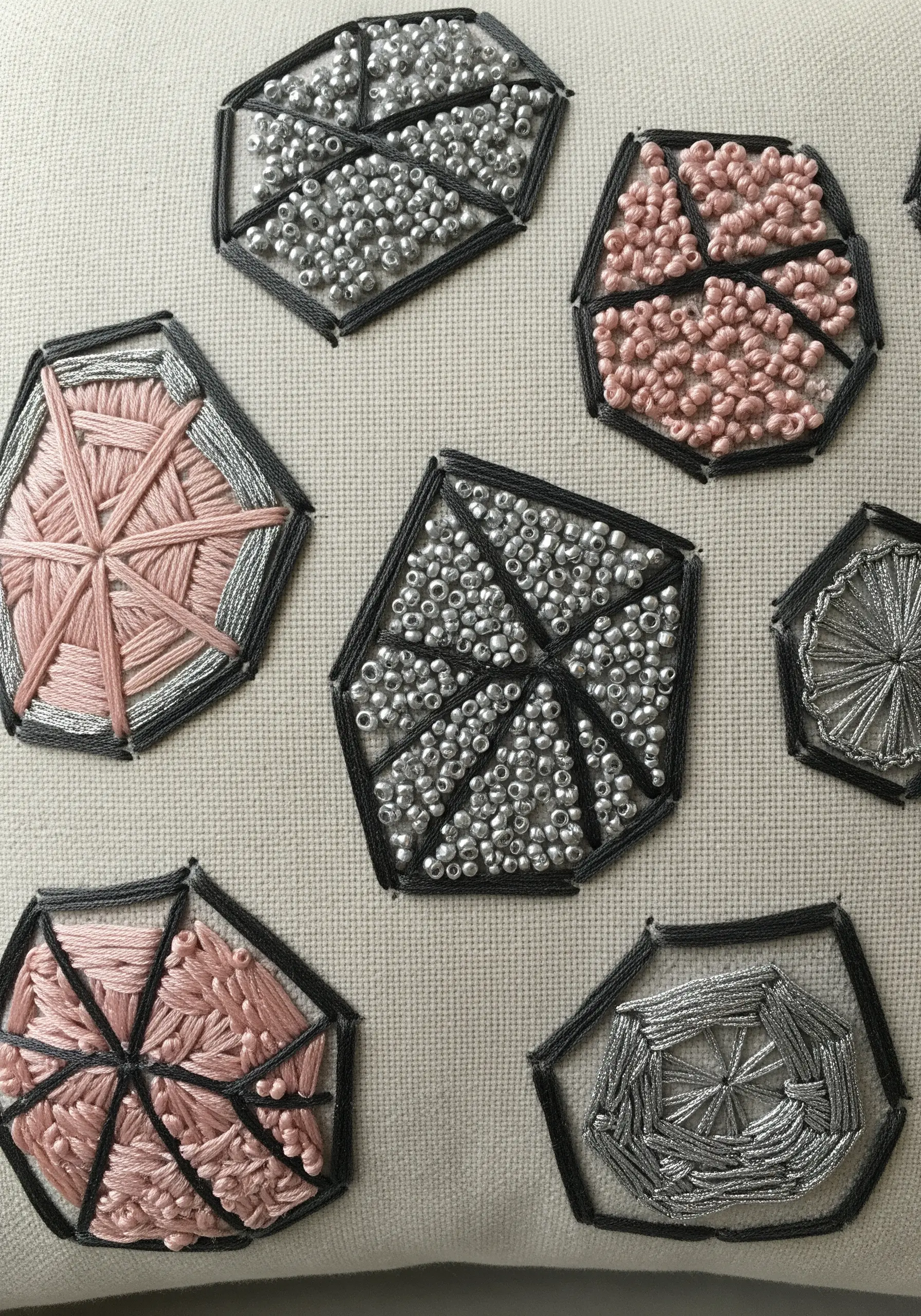 Geometric shapes on a pillow filled with different textures, including beads and woven thread.