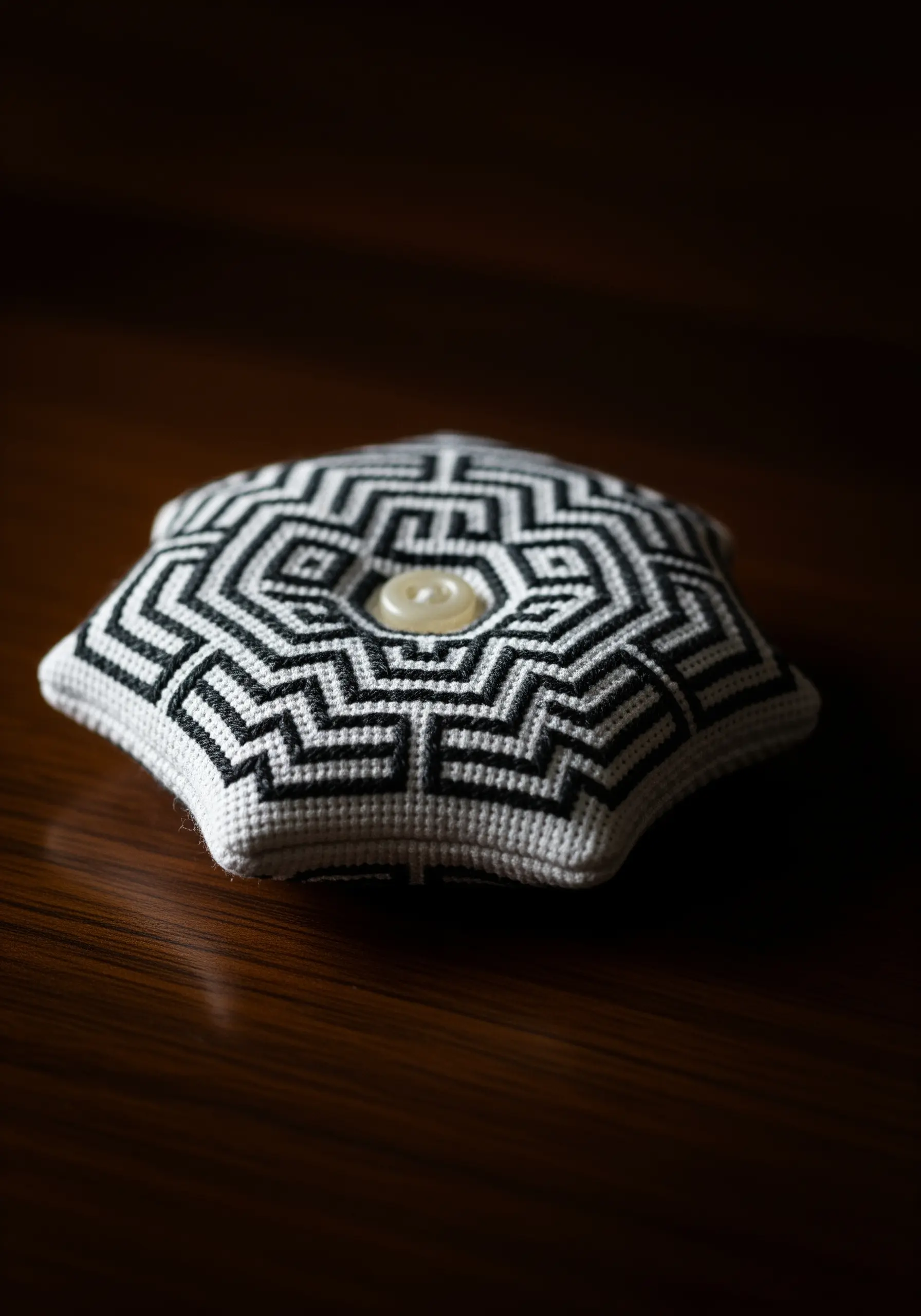A star-shaped pincushion decorated with a complex black-and-white geometric Blackwork pattern.