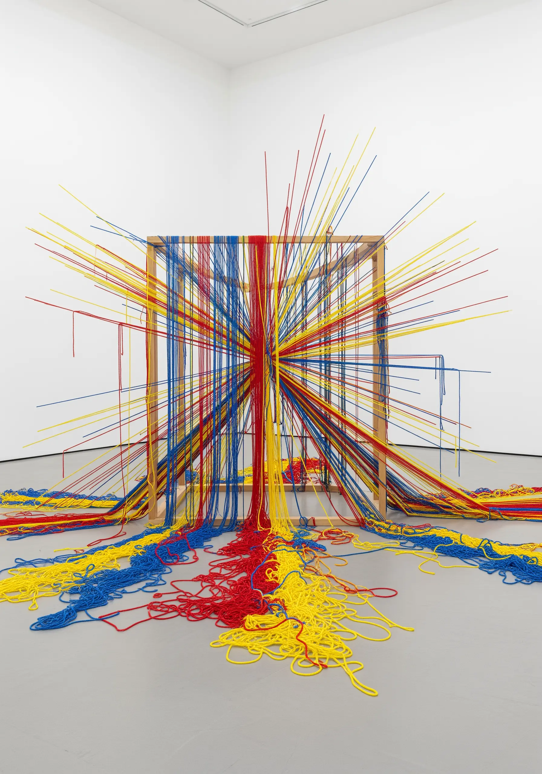 Installation of red, yellow, and blue threads exploding from a wooden cube