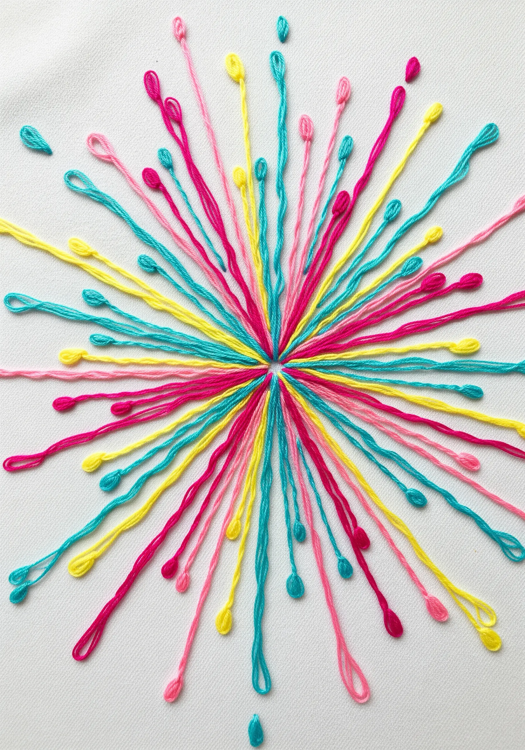 A playful starburst of detached chain stitches in bright pink, yellow, and turquoise.