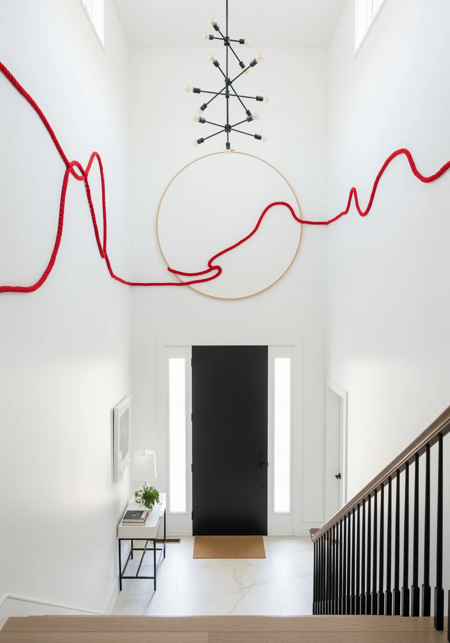 A large-scale installation where a red cord travels from a hoop across a white wall.