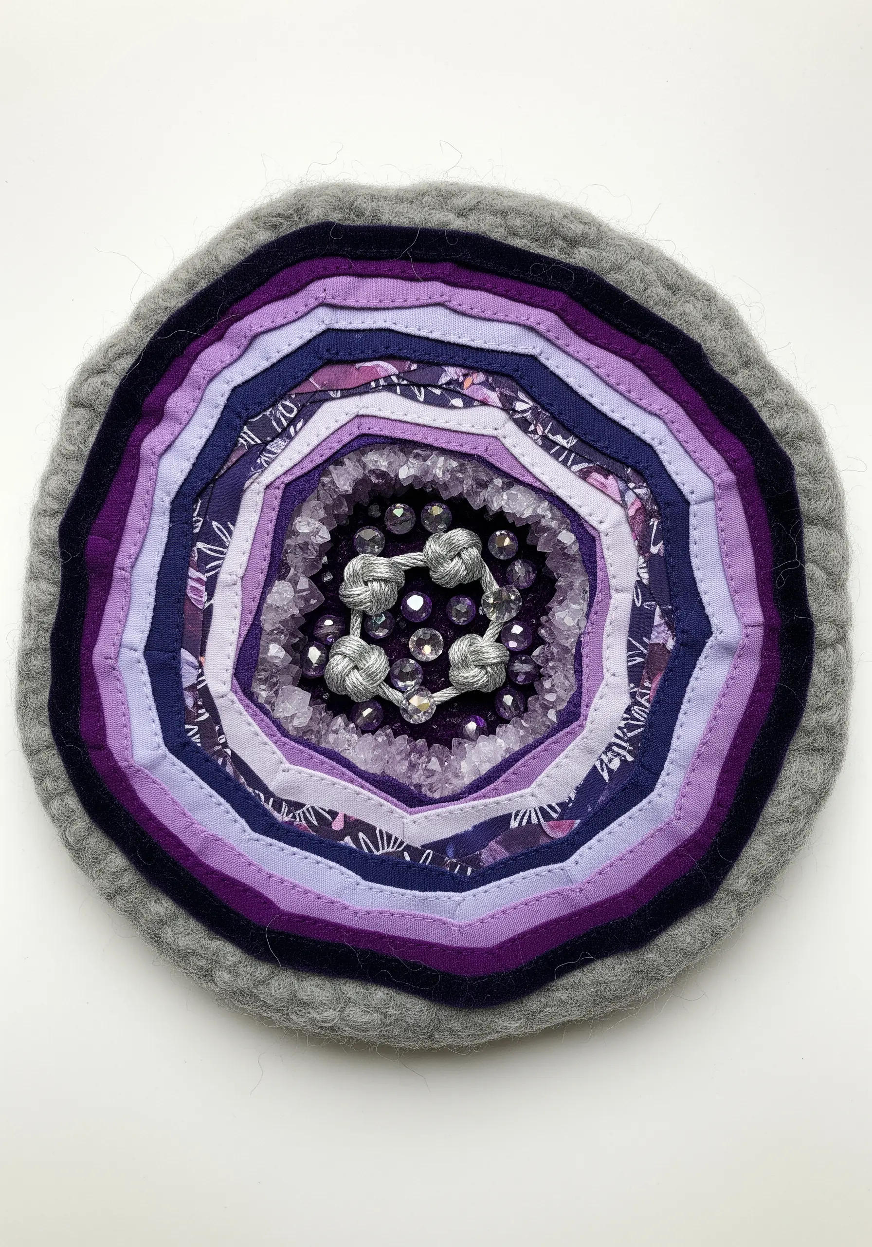 Fabric collage geode with layered purple fabrics and a center of crystal beads.