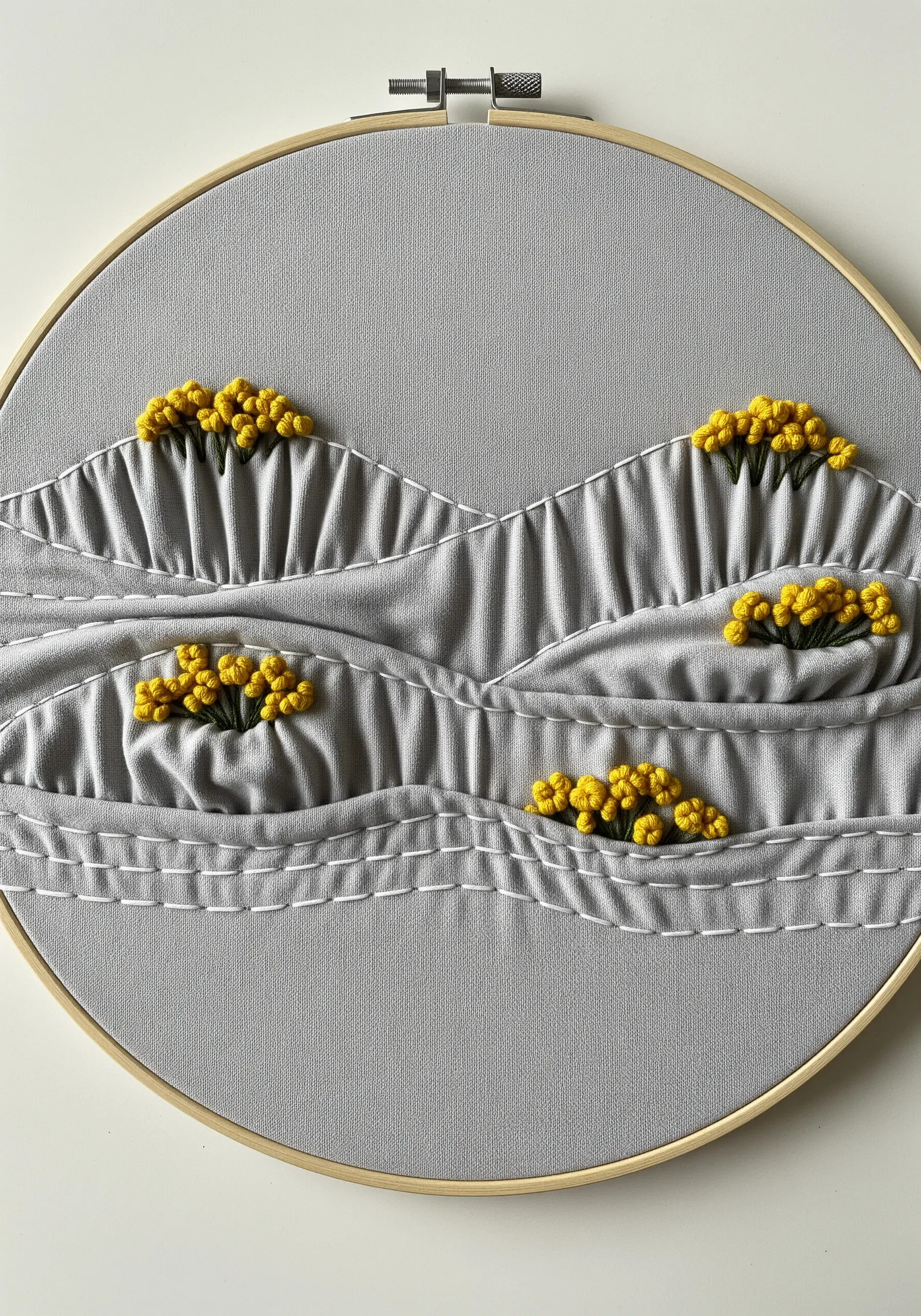 Grey fabric gathered into dimensional hills, accented with yellow French knots.