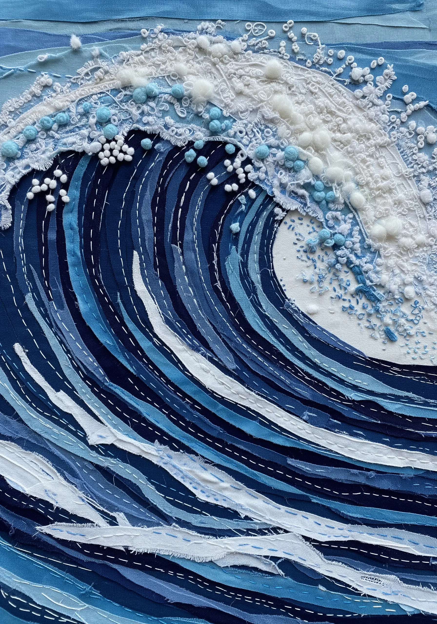 Ocean wave made from layered blue fabric strips with French knot sea foam.