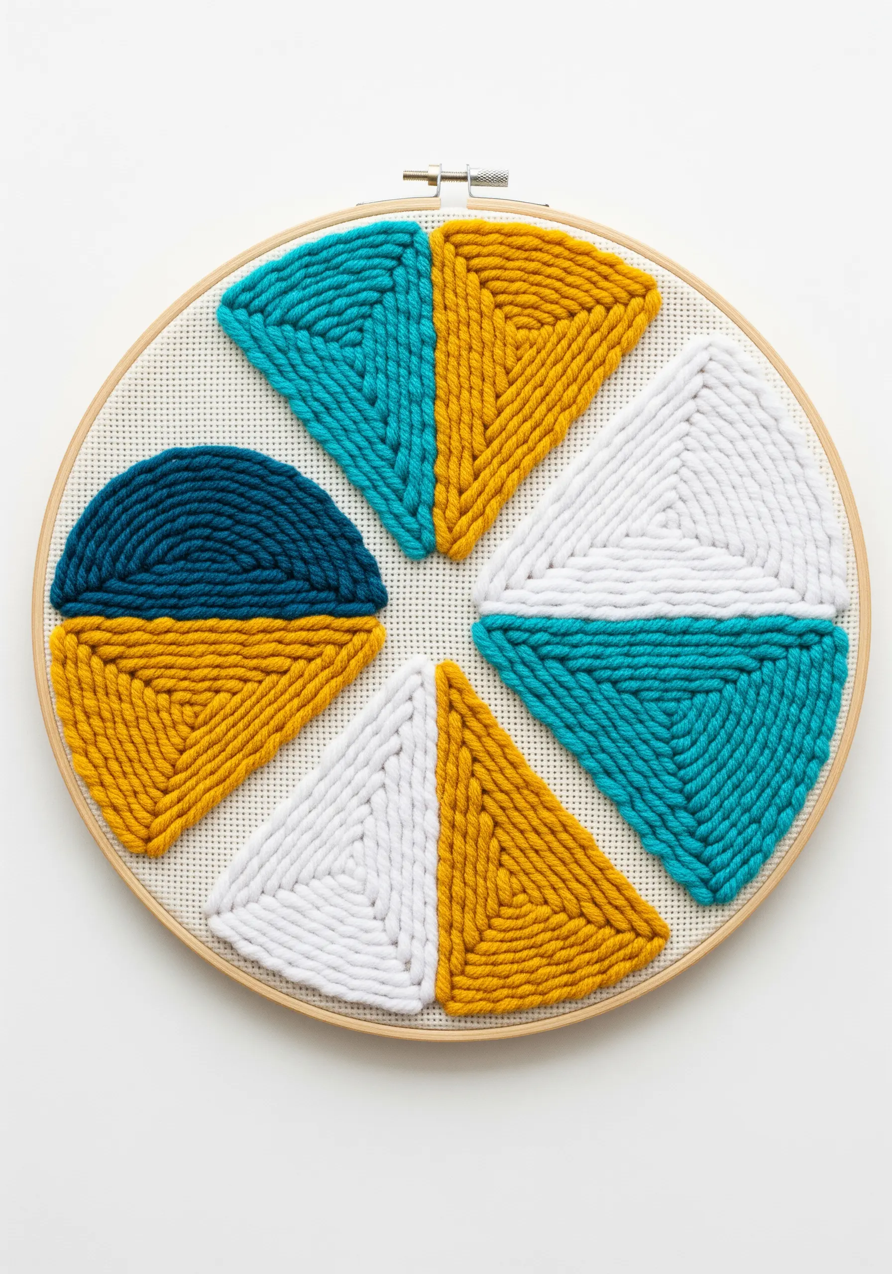Geometric punch needle hoop art with sections of teal, yellow, and white yarn.