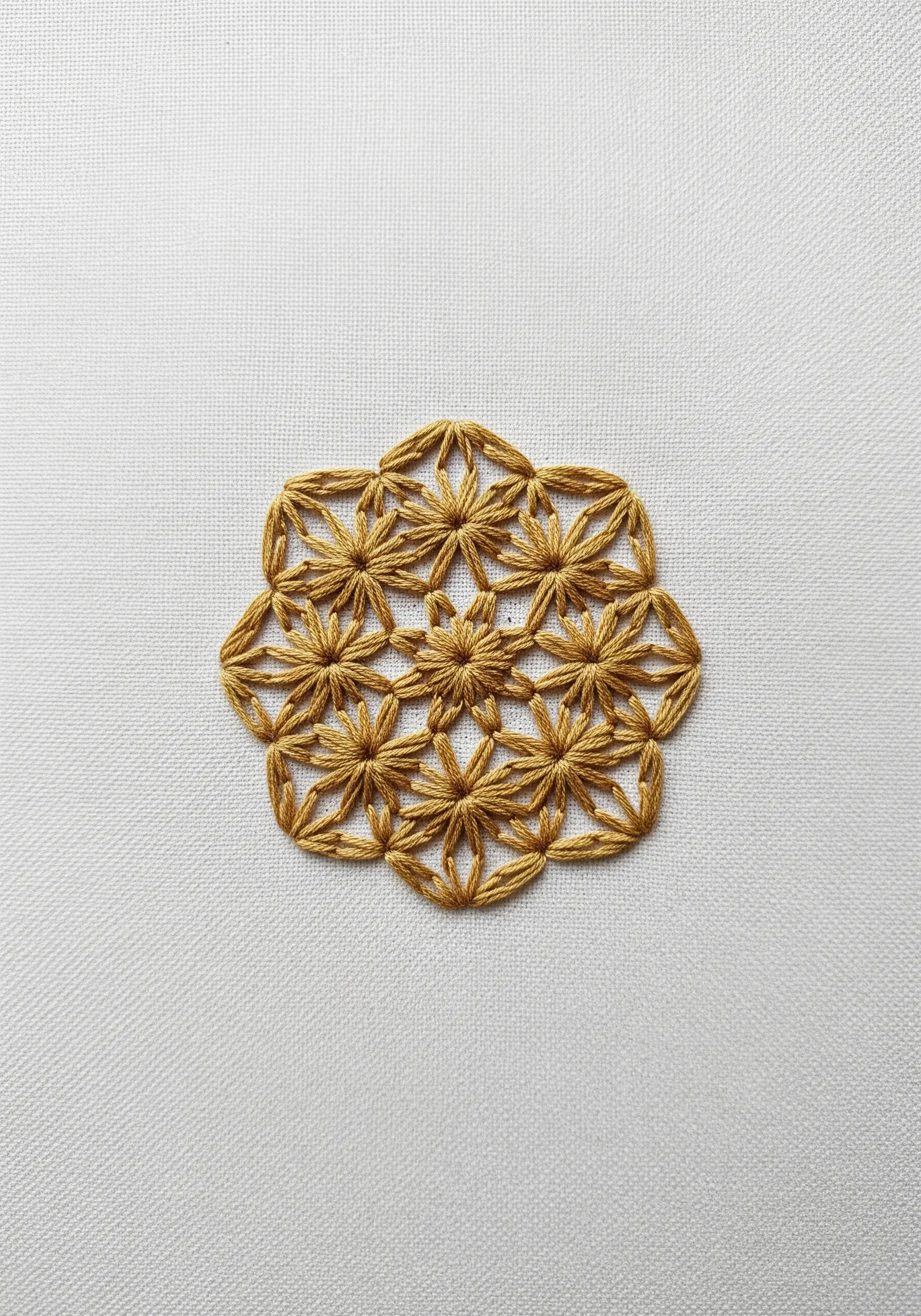 A golden-yellow mandala made of interlocking star shapes formed by straight stitches.