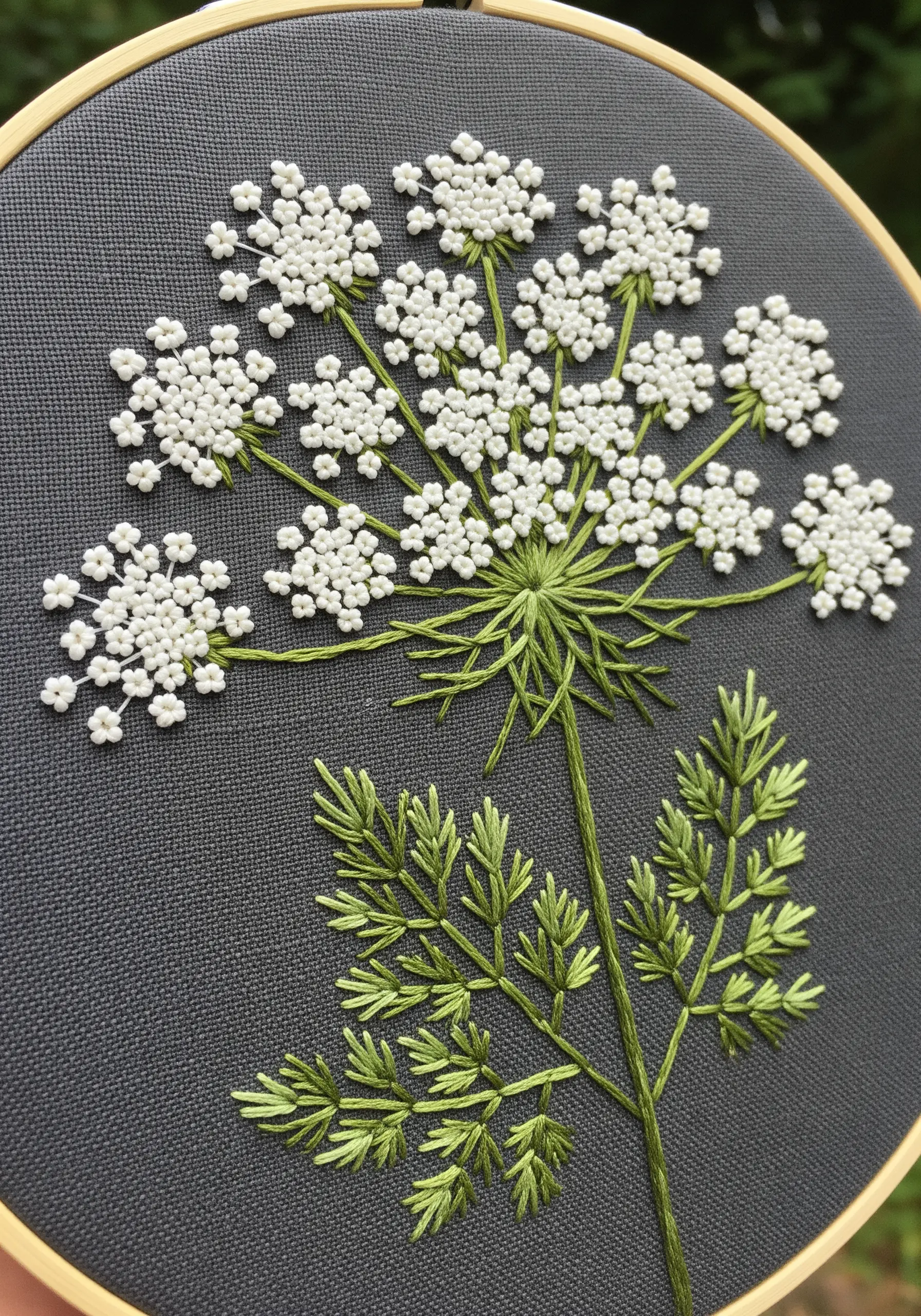 White French knot clusters forming Queen Anne's Lace on dark gray fabric.