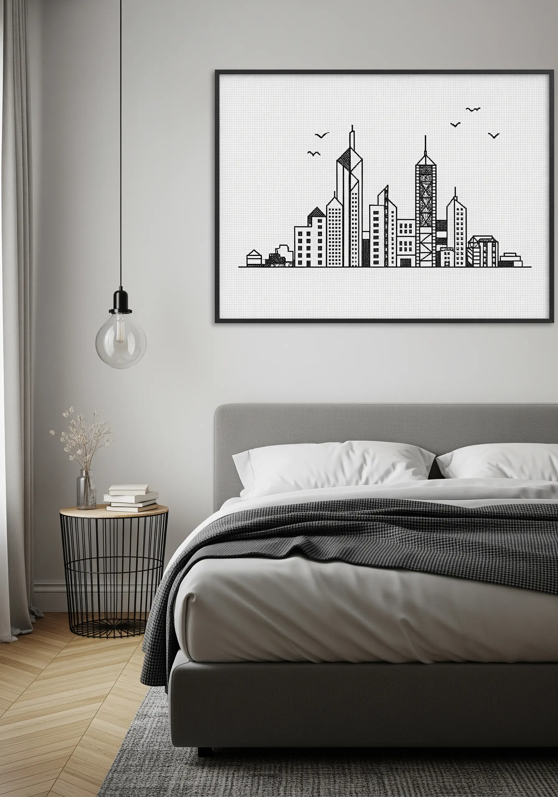 A framed black and white cross-stitch pattern of a city skyline above a modern bed.
