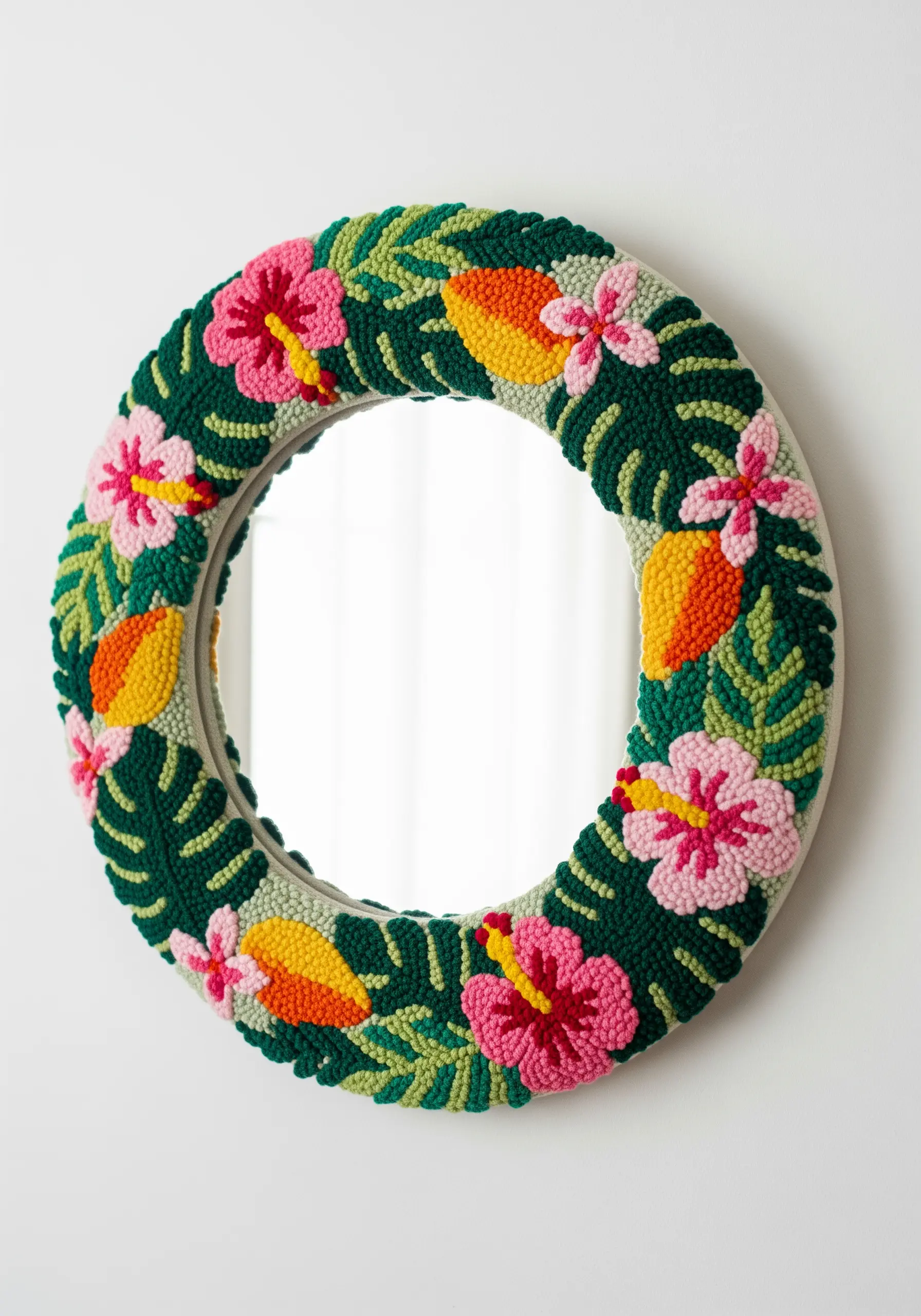 A round mirror framed with a colorful, textured punch needle design of tropical flowers and leaves.