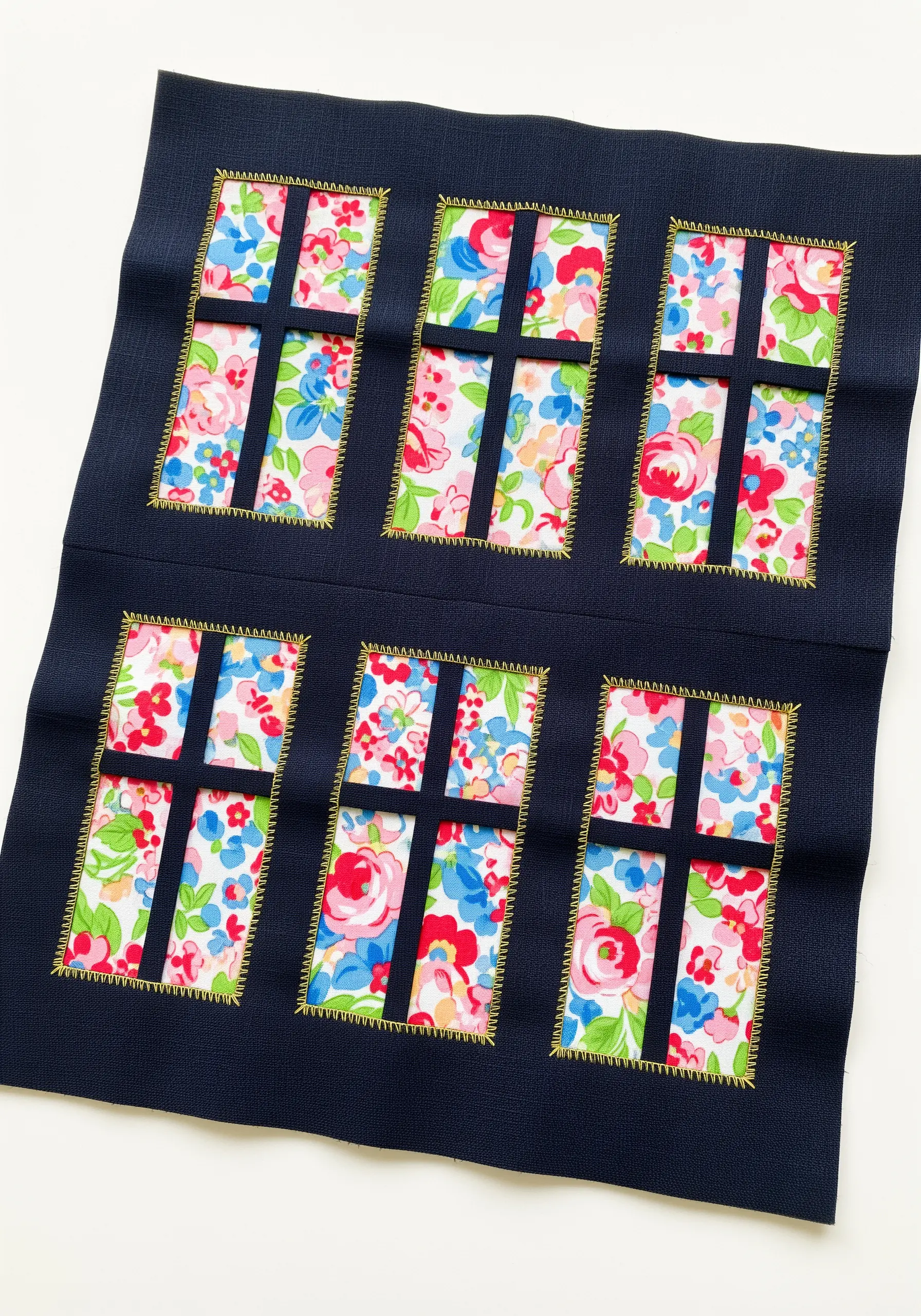 Reverse appliqué creating window panes that reveal a floral fabric underneath.