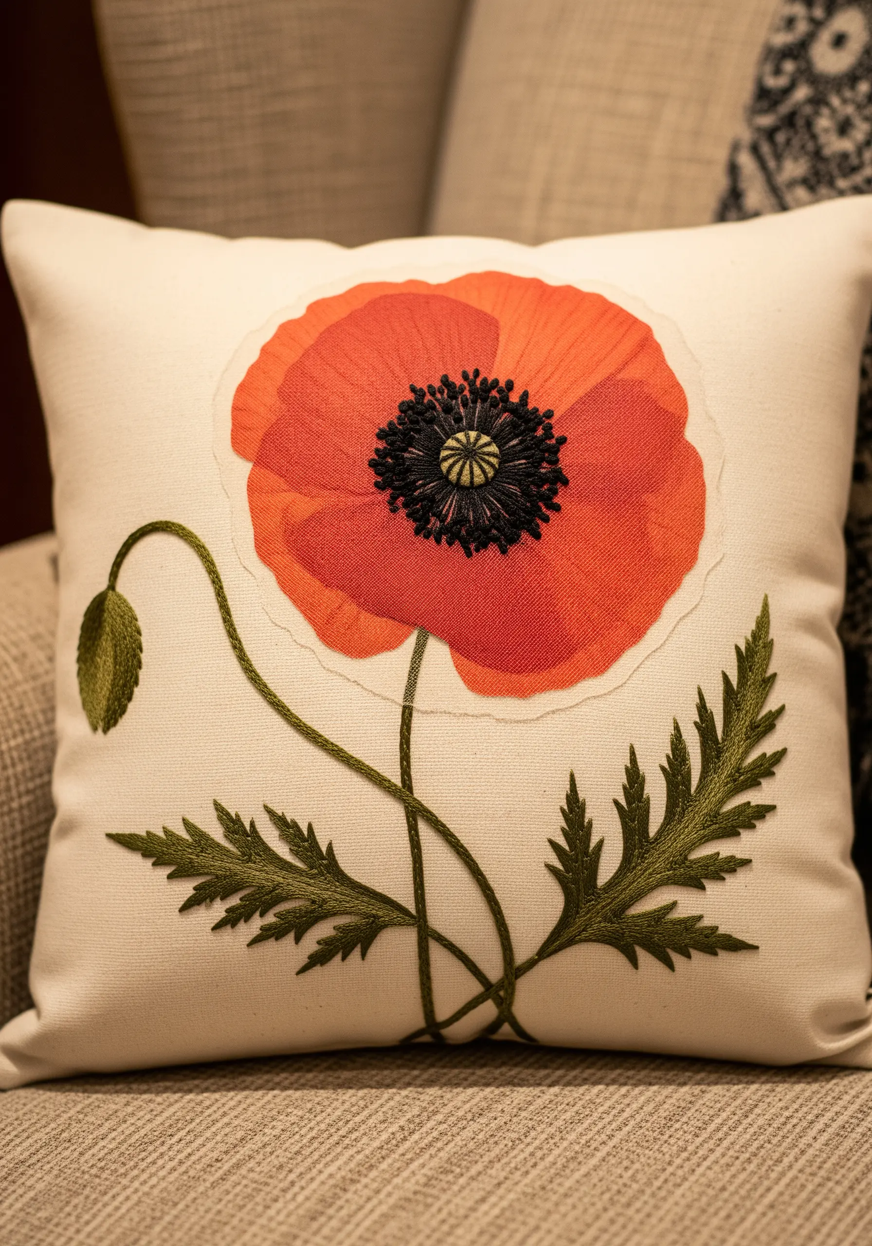 A red poppy on a cushion, with embroidered leaves and a textured center.