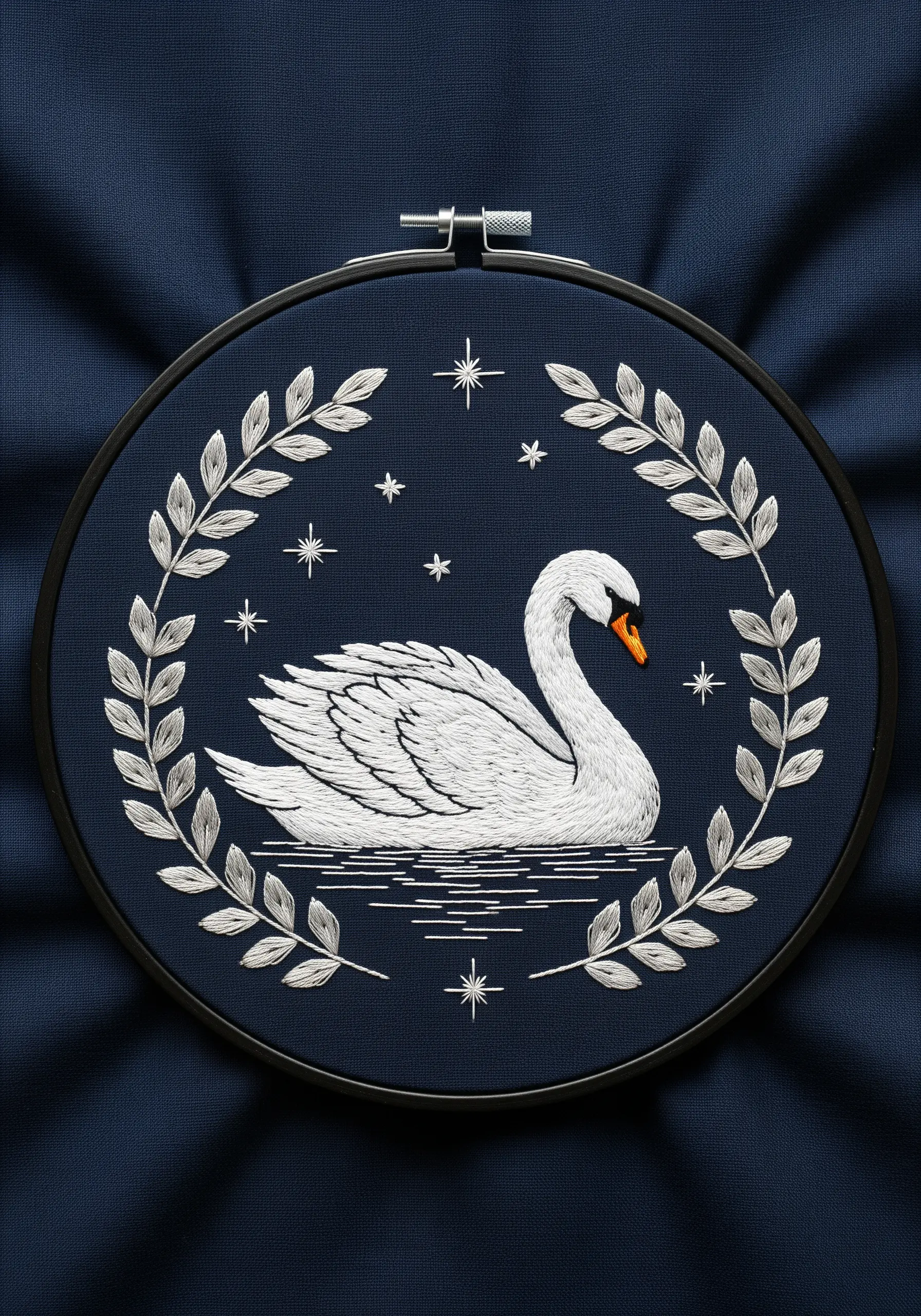 A white swan on navy fabric, framed by a silver wreath and tiny embroidered stars.