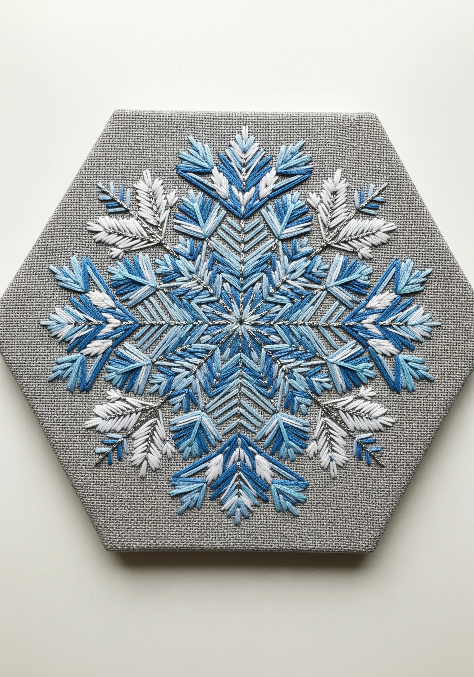 A blue and white snowflake mandala stretched and mounted on a hexagonal canvas.