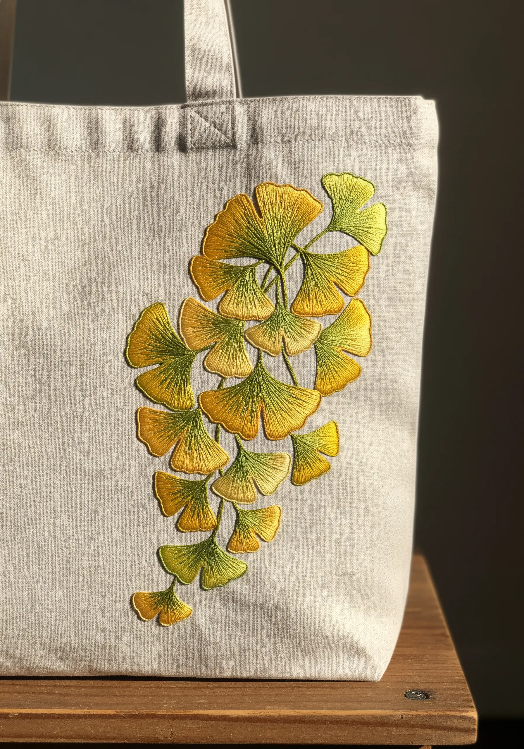 Golden ginkgo leaf embroidery with satin stitch gradients on a canvas tote bag.