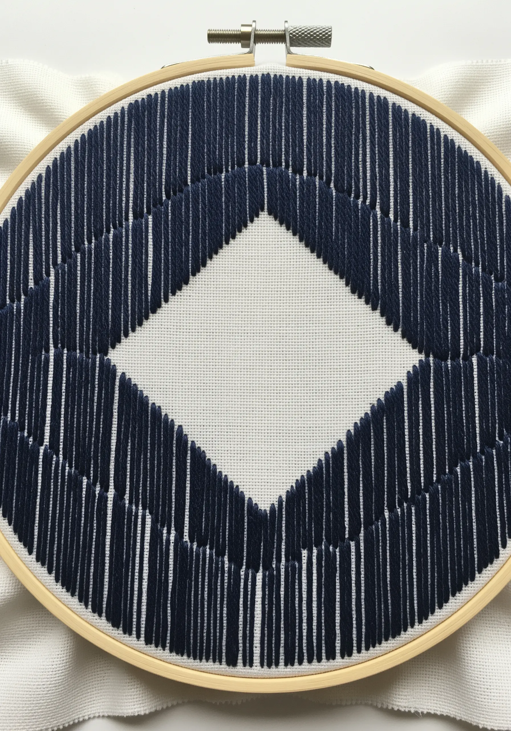 A diamond shape created by filling the surrounding area with dark blue vertical stitches.