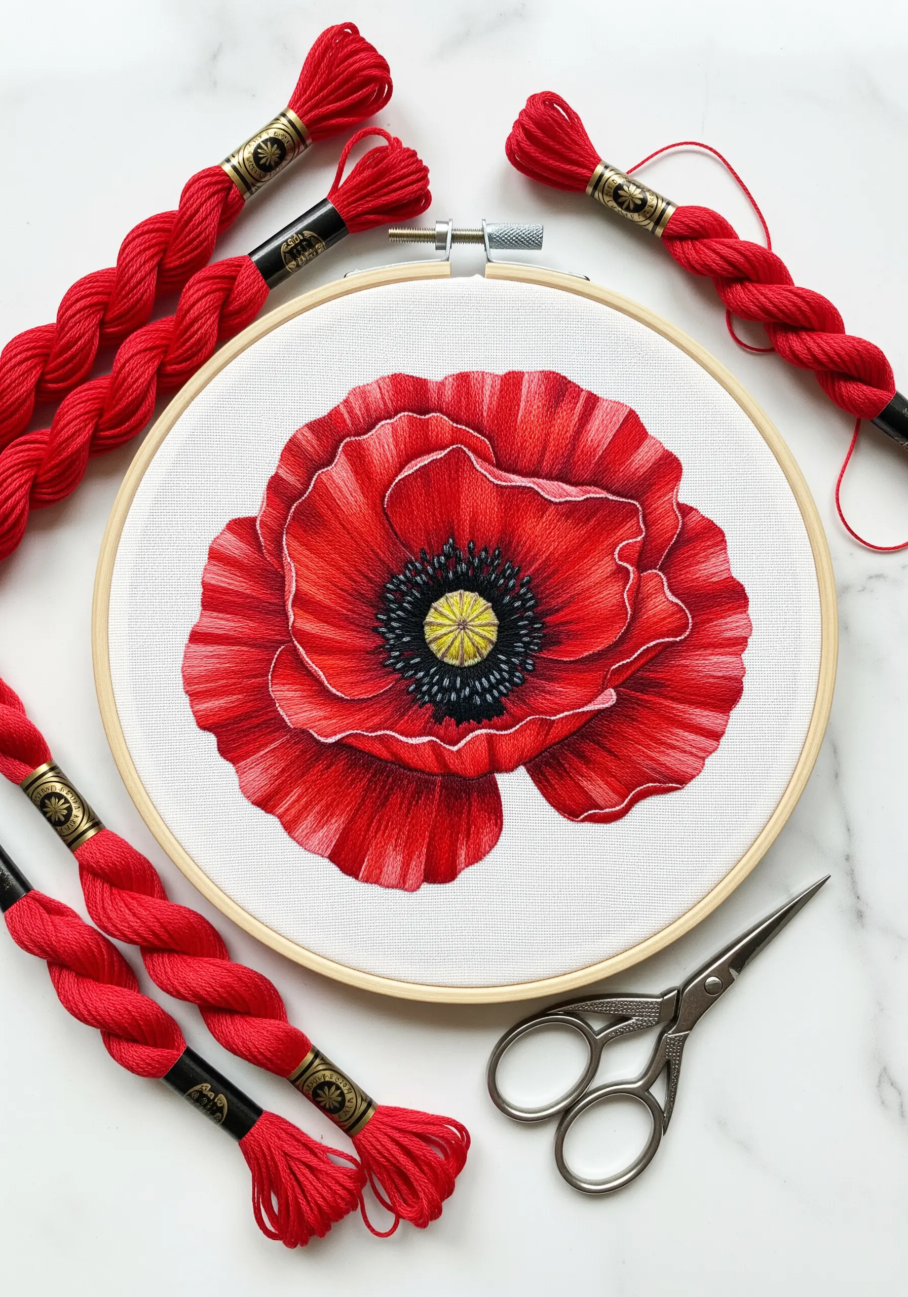 Red poppy embroidery with detailed thread shading and black center on white fabric