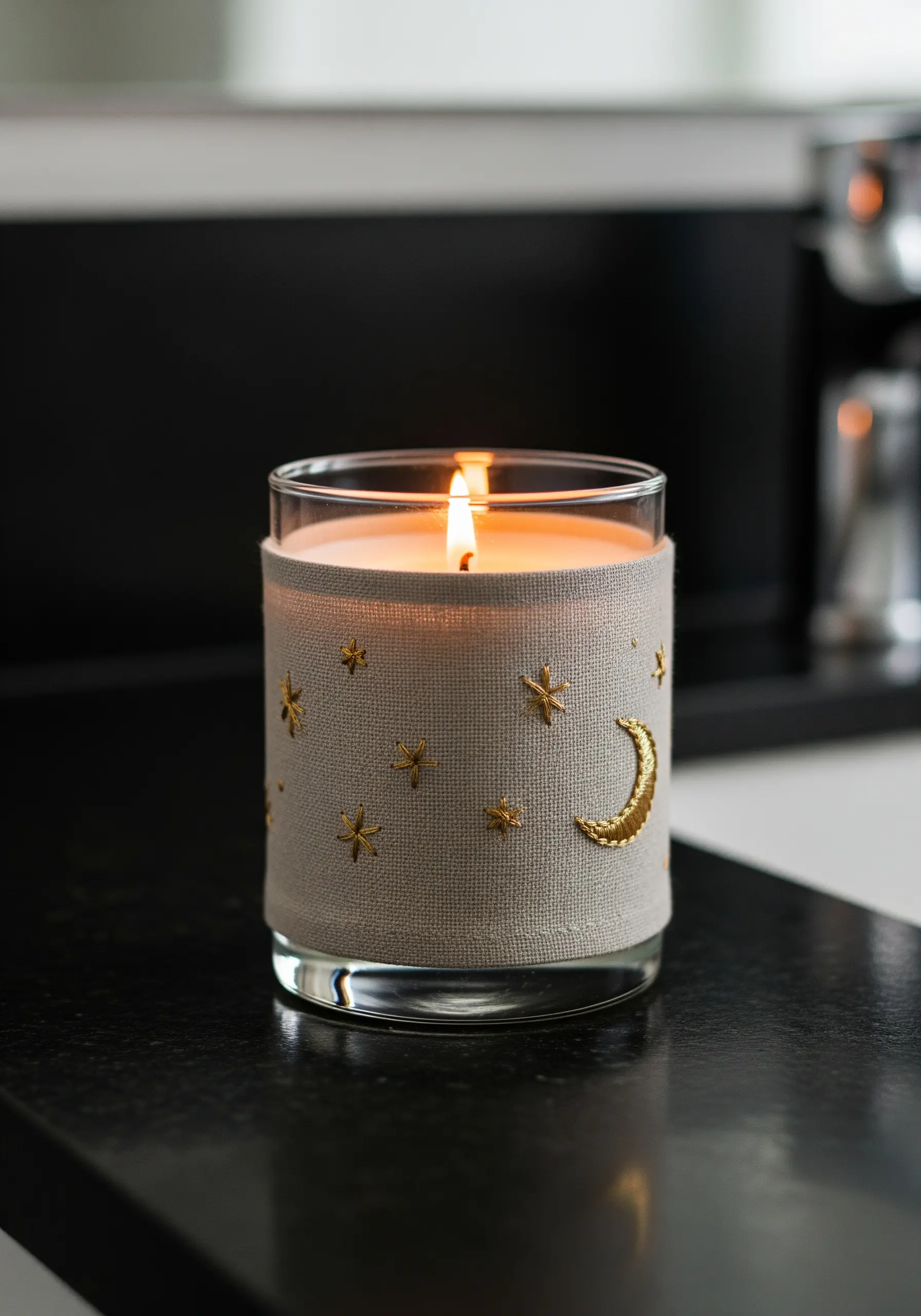 A linen candle wrap embroidered with a gold metallic crescent moon and stars.
