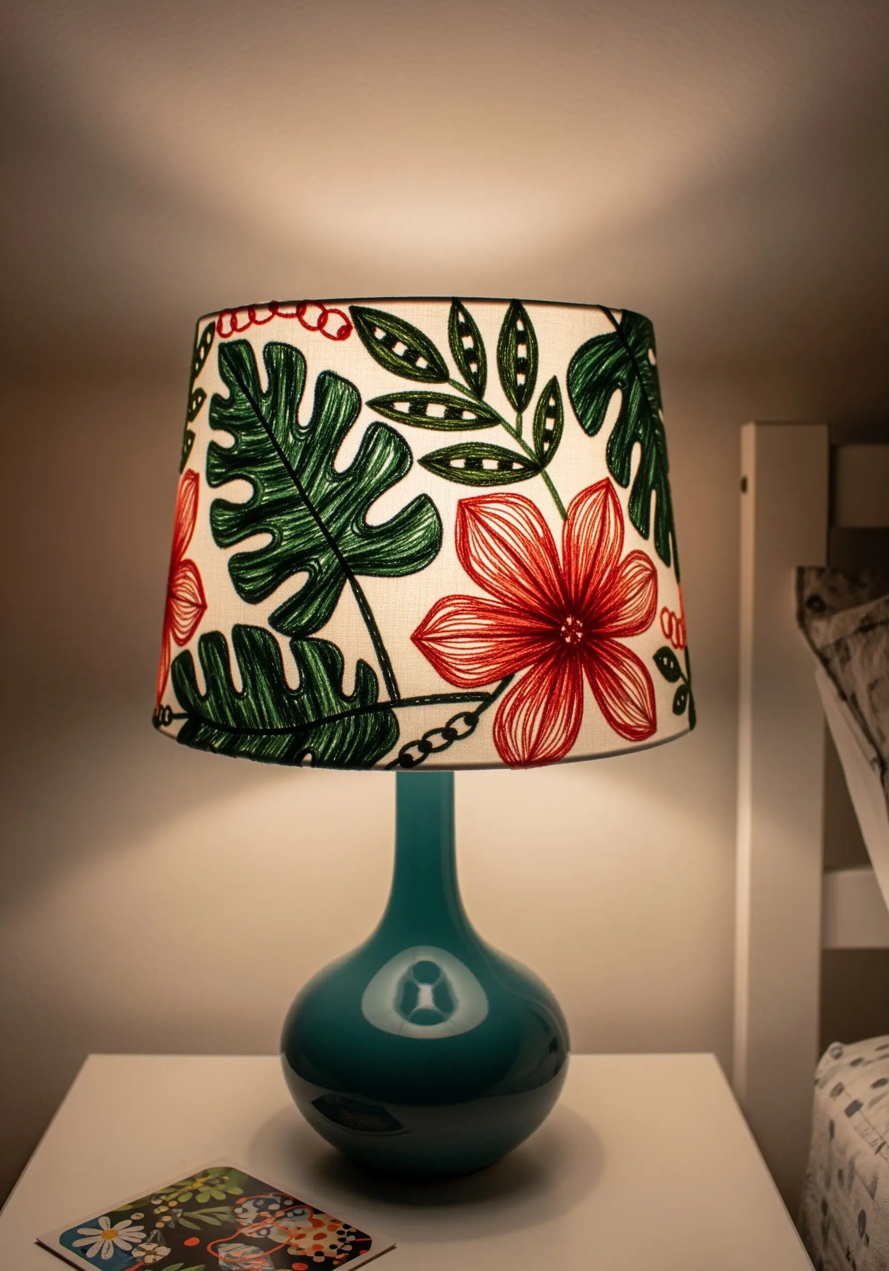 A lampshade with bold, colorful embroidery of tropical leaves and flowers.