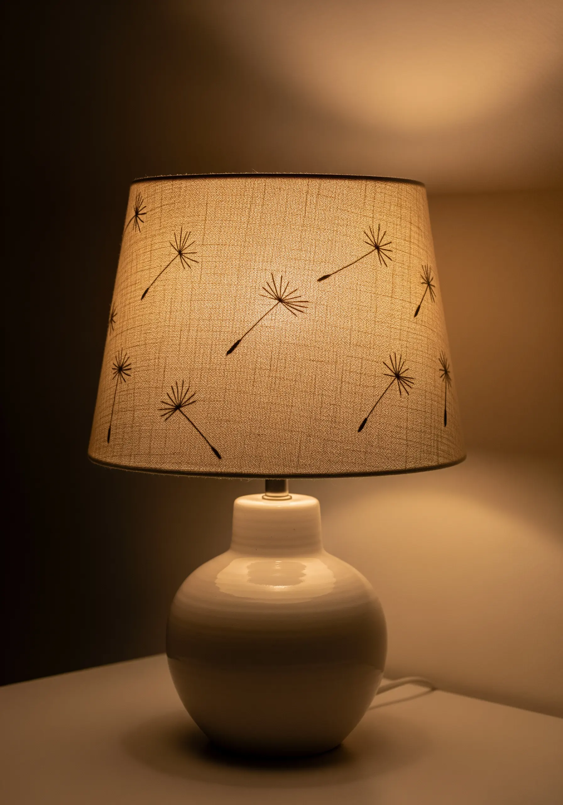 Minimalist dandelion seed embroidery on a fabric lampshade.