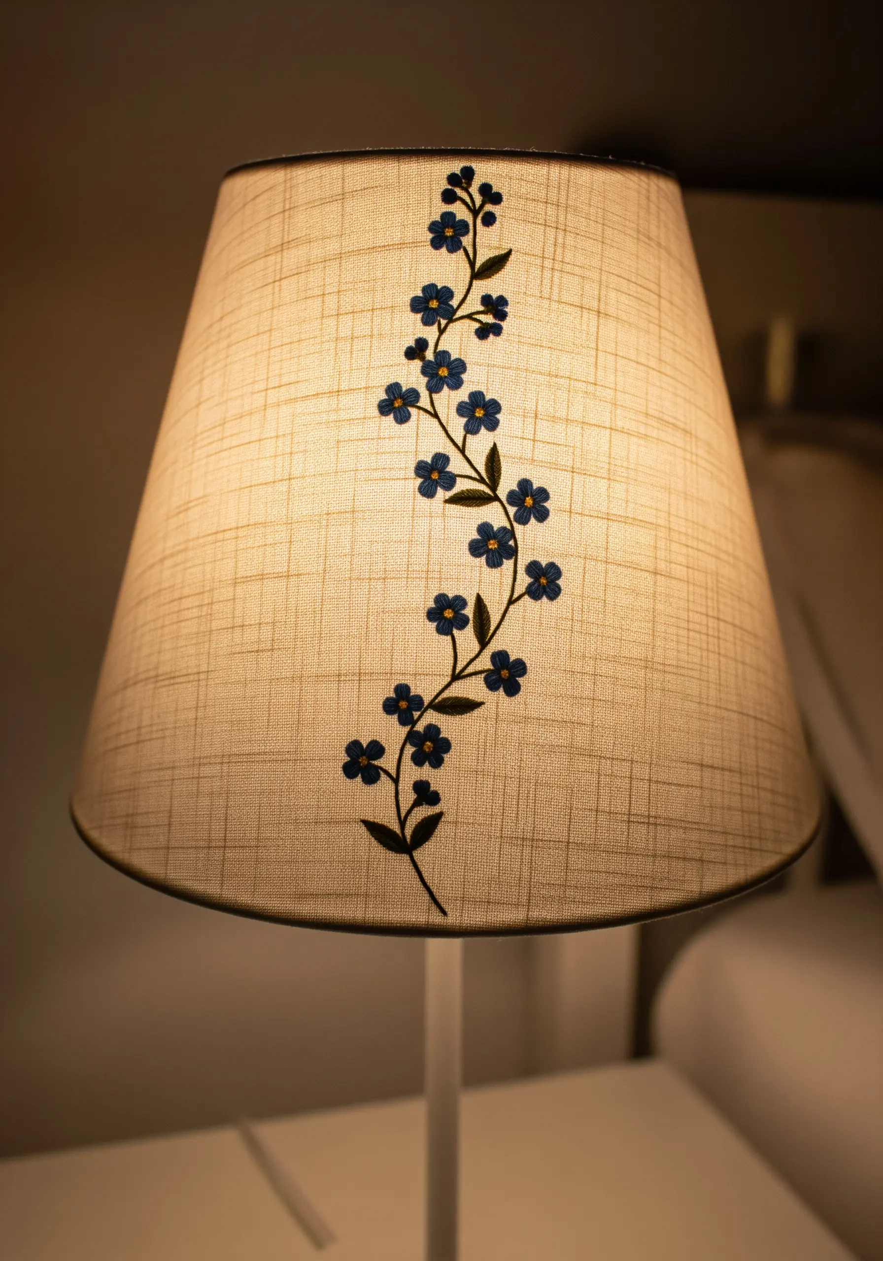 A climbing blue floral vine embroidered vertically on a fabric lampshade.