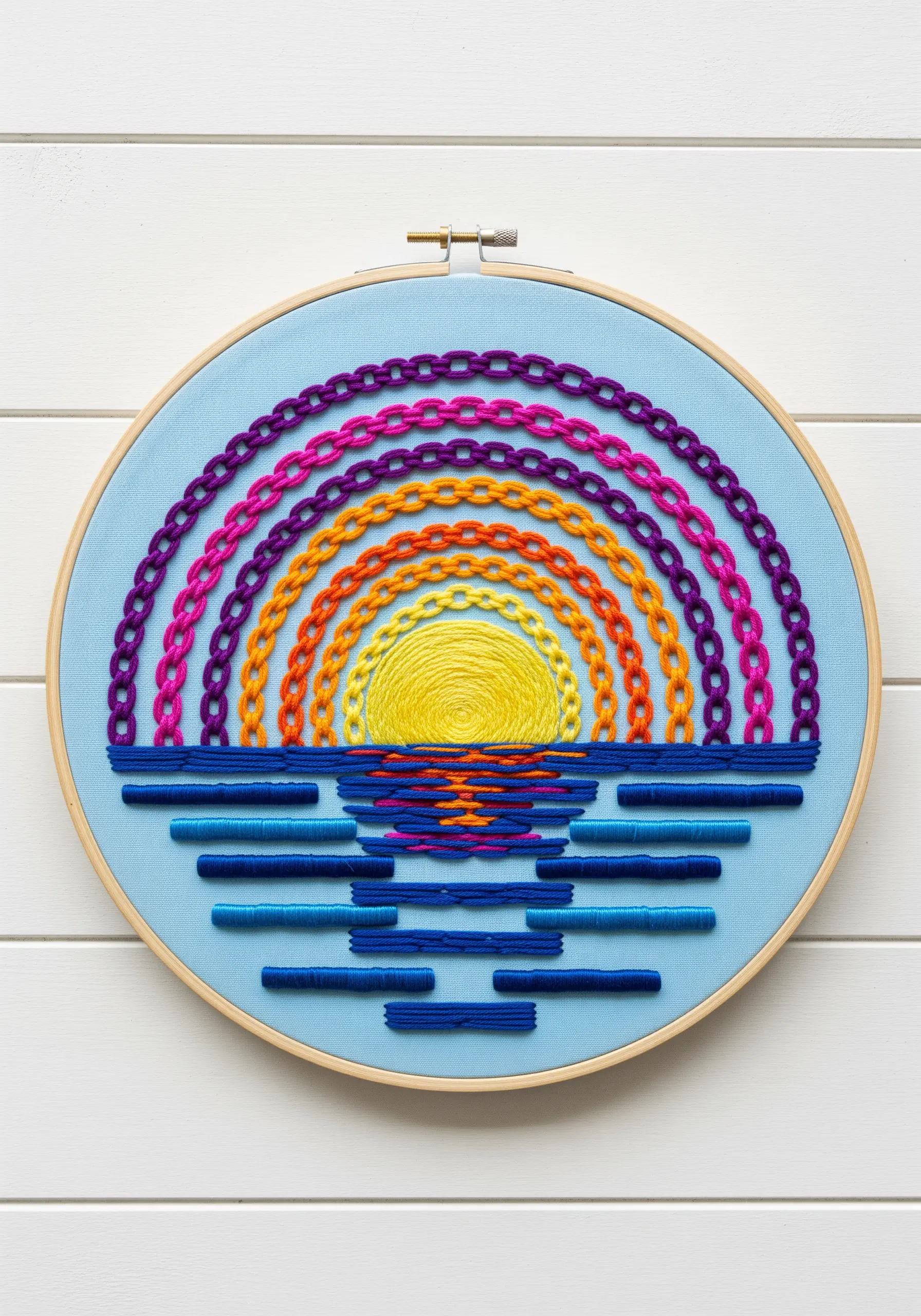 Rainbow sunset mandala over water, using chain stitch for the sky and satin stitch for reflections.