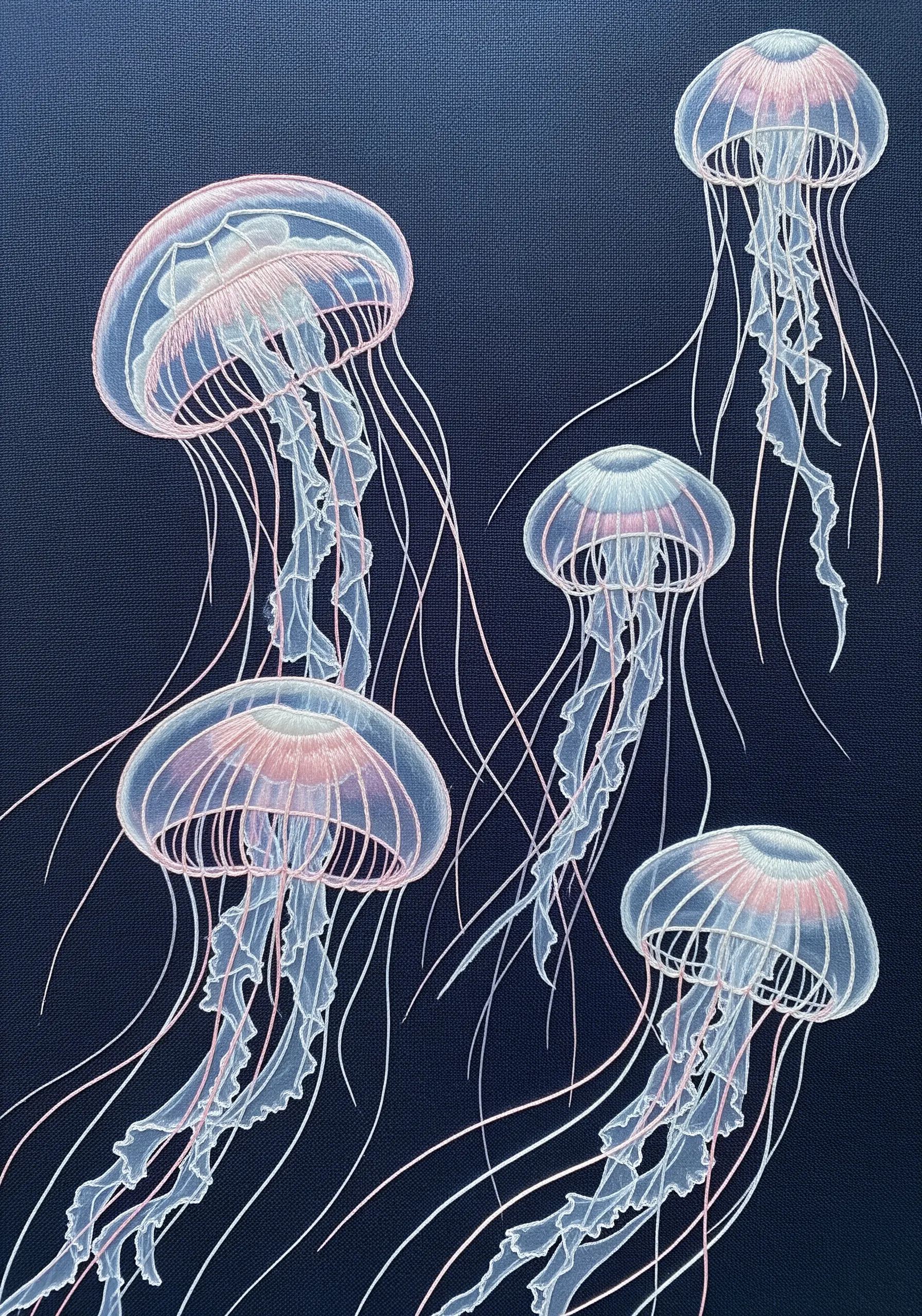 Embroidered jellyfish with translucent bodies stitched in light thread on a dark navy canvas.