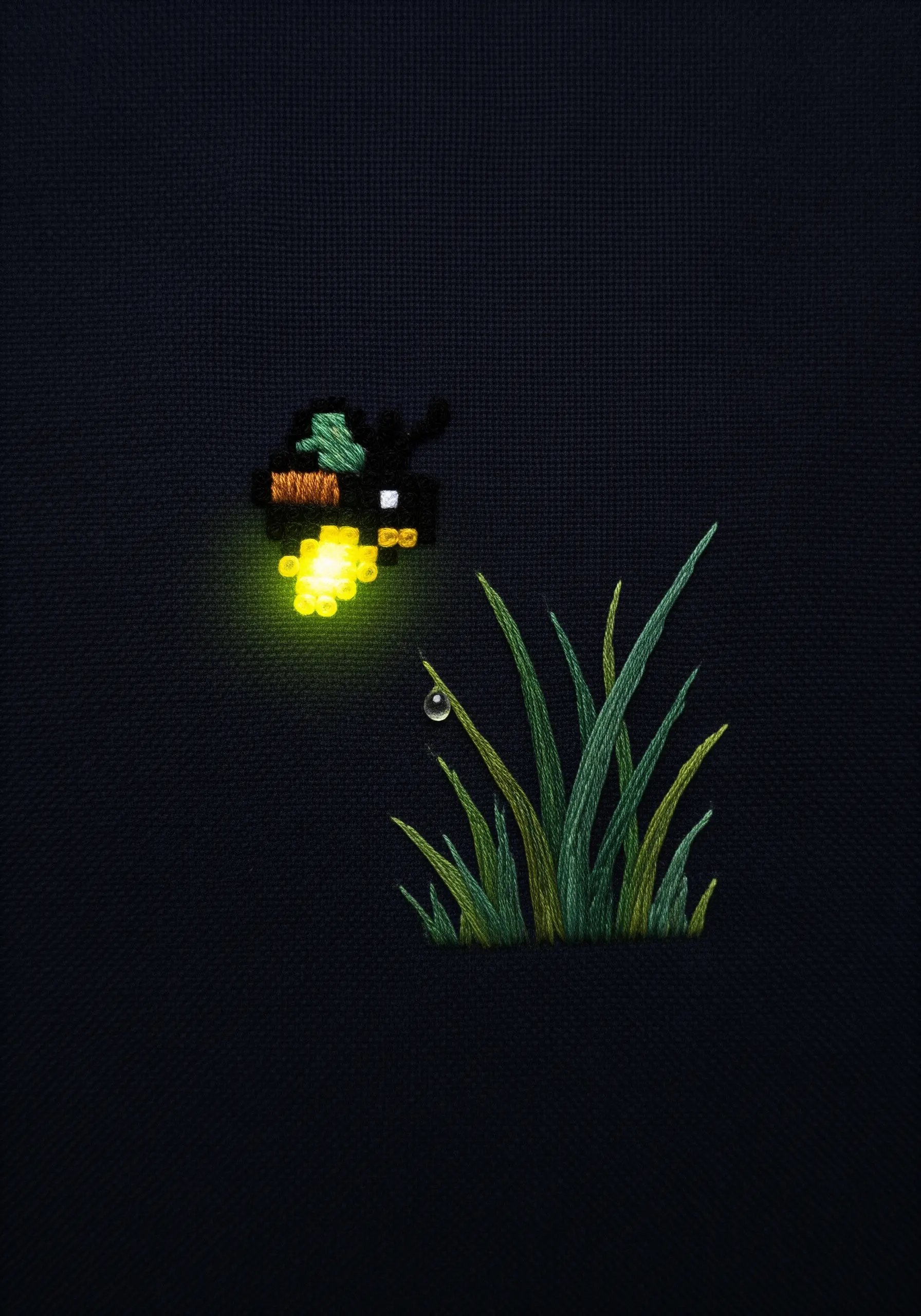 A tiny pixel art firefly embroidery with a real LED light making it glow.