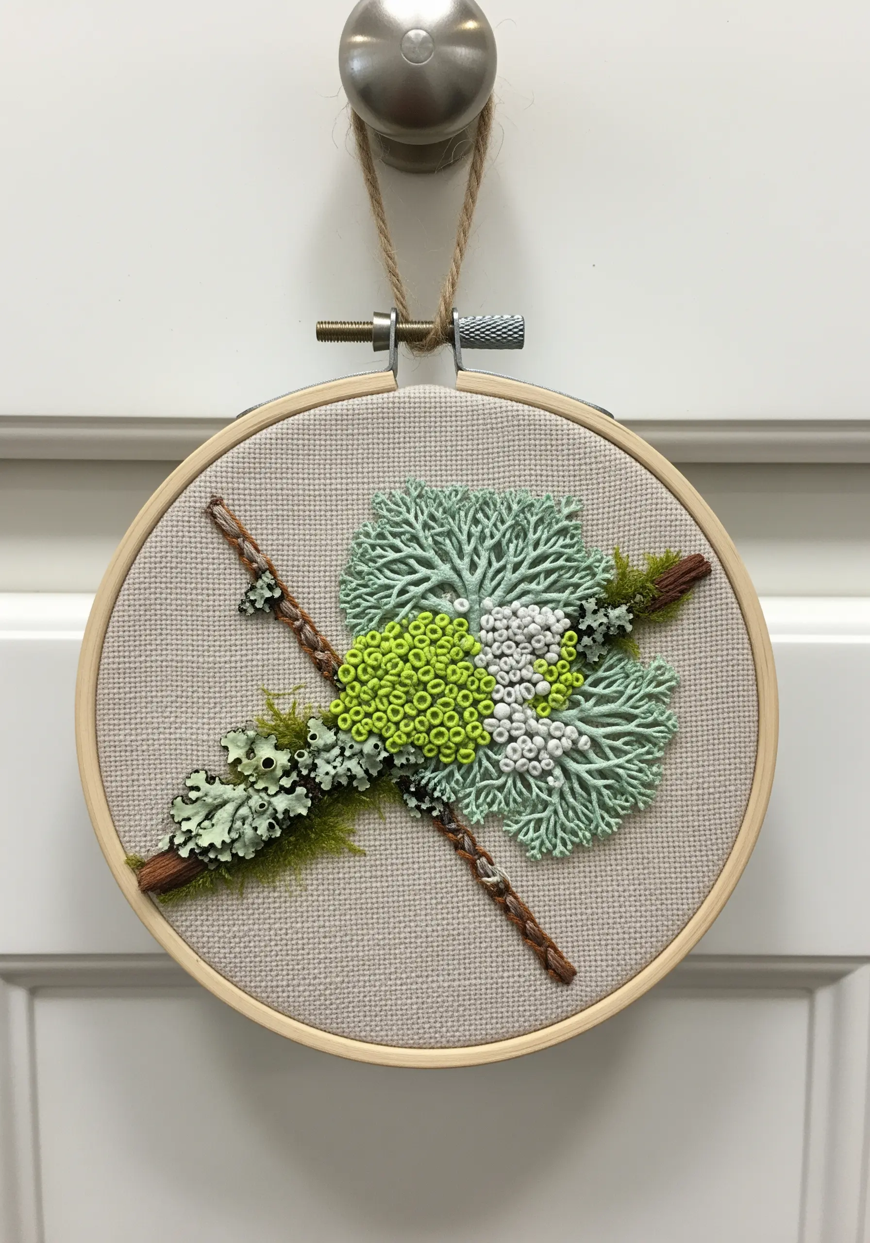 Mixed-media embroidery featuring real twigs and dense French knots simulating lichen and moss.